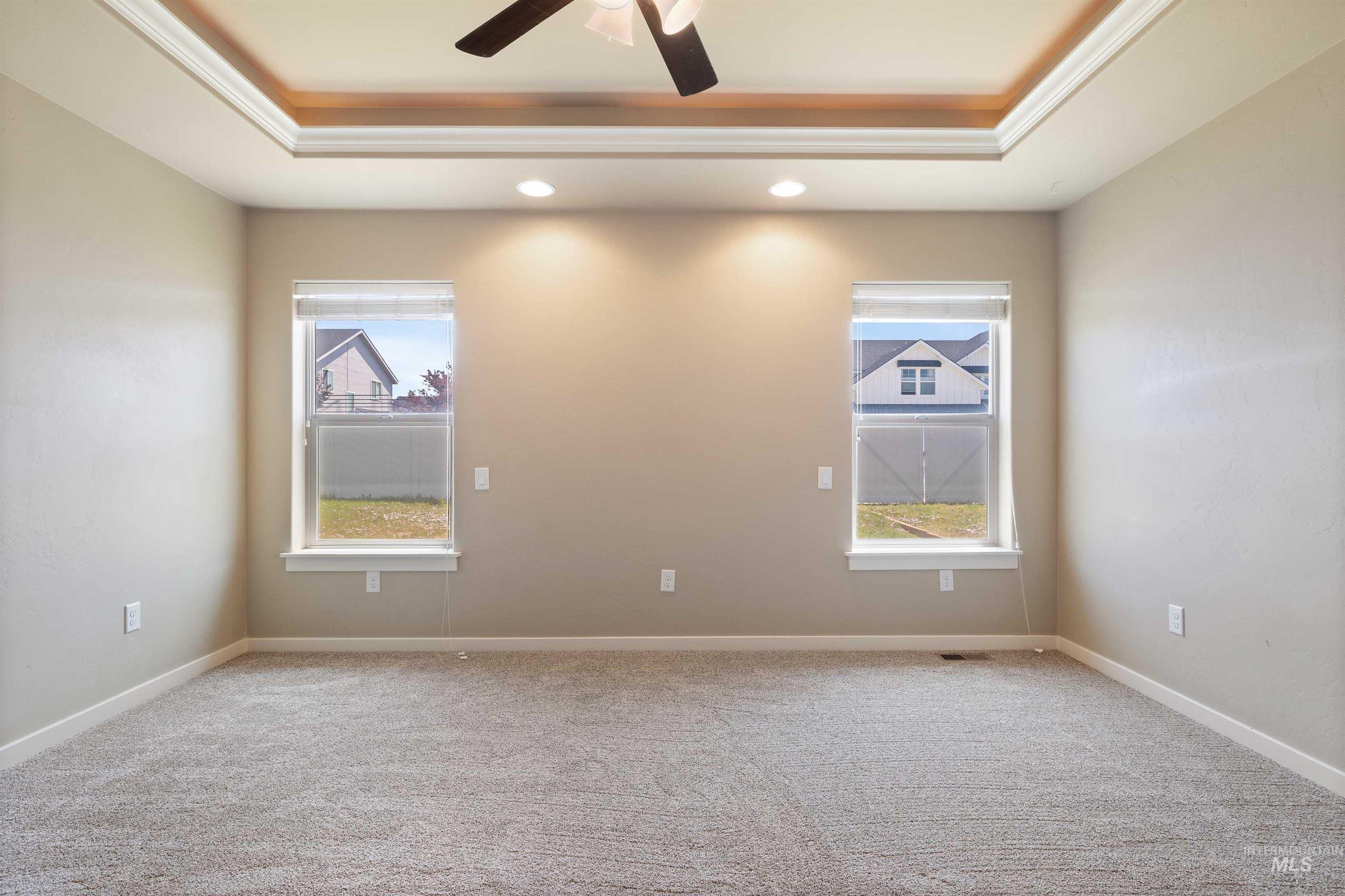 Carpeted spare room with a tray ceiling, a ceiling fan, recessed lighting, and crown molding