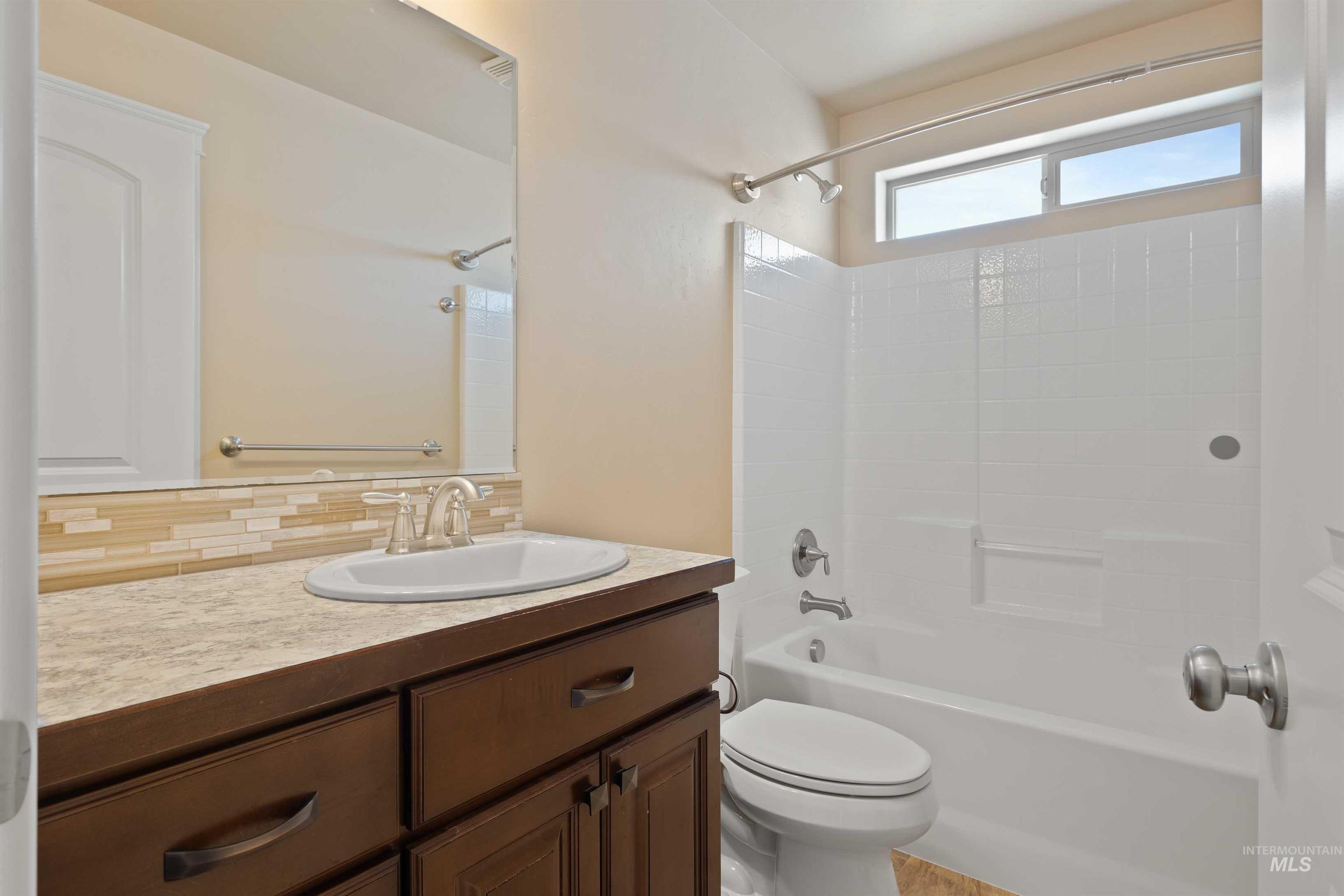 Bathroom with shower / bathtub combination, vanity, and backsplash