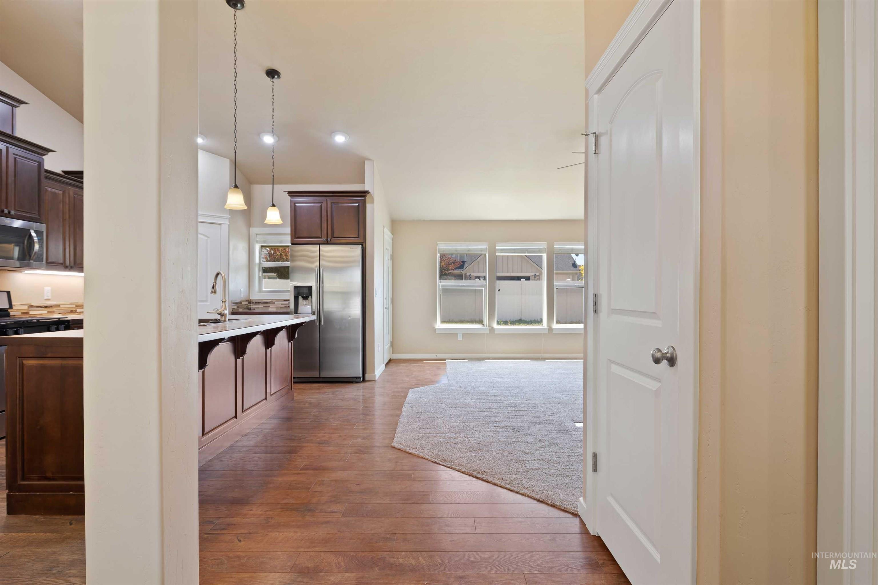 Kitchen with appliances with stainless steel finishes, a kitchen bar, light countertops, and dark brown cabinets