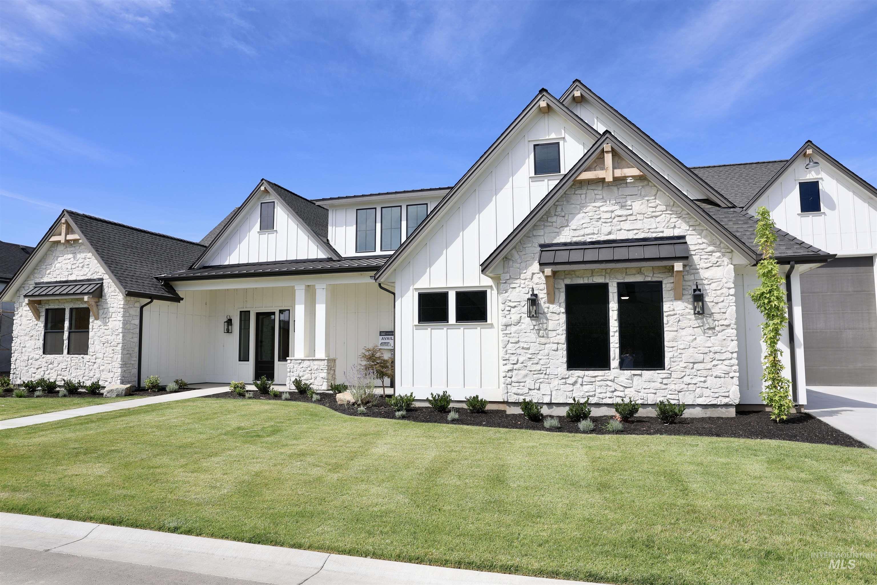 View of front of property with a standing seam roof, board and batten siding, stone siding, a metal roof, and a front lawn