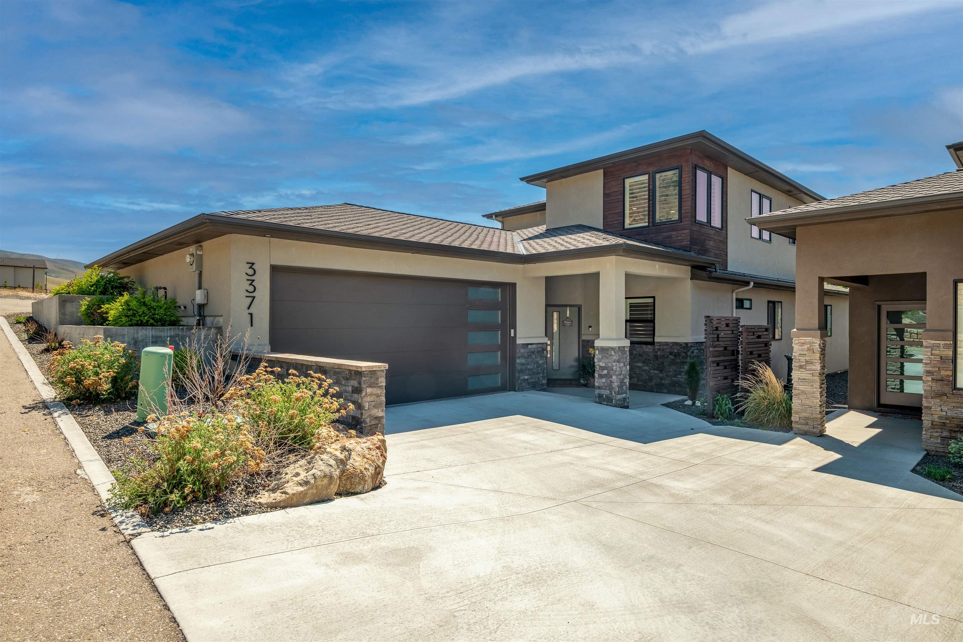 Prairie-style home with stucco siding, an attached garage, concrete driveway, and stone siding