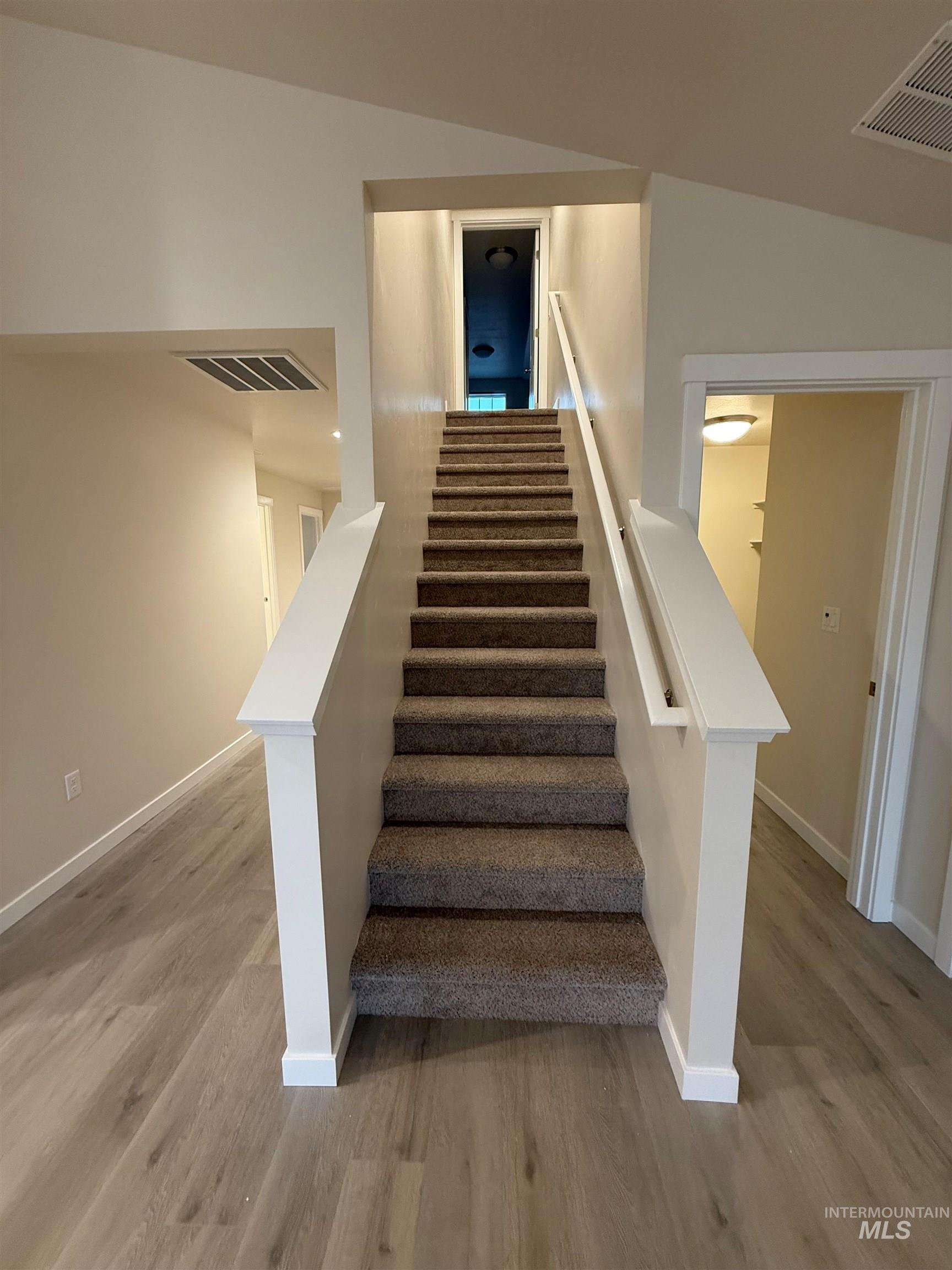 Stairway with wood finished floors and baseboards