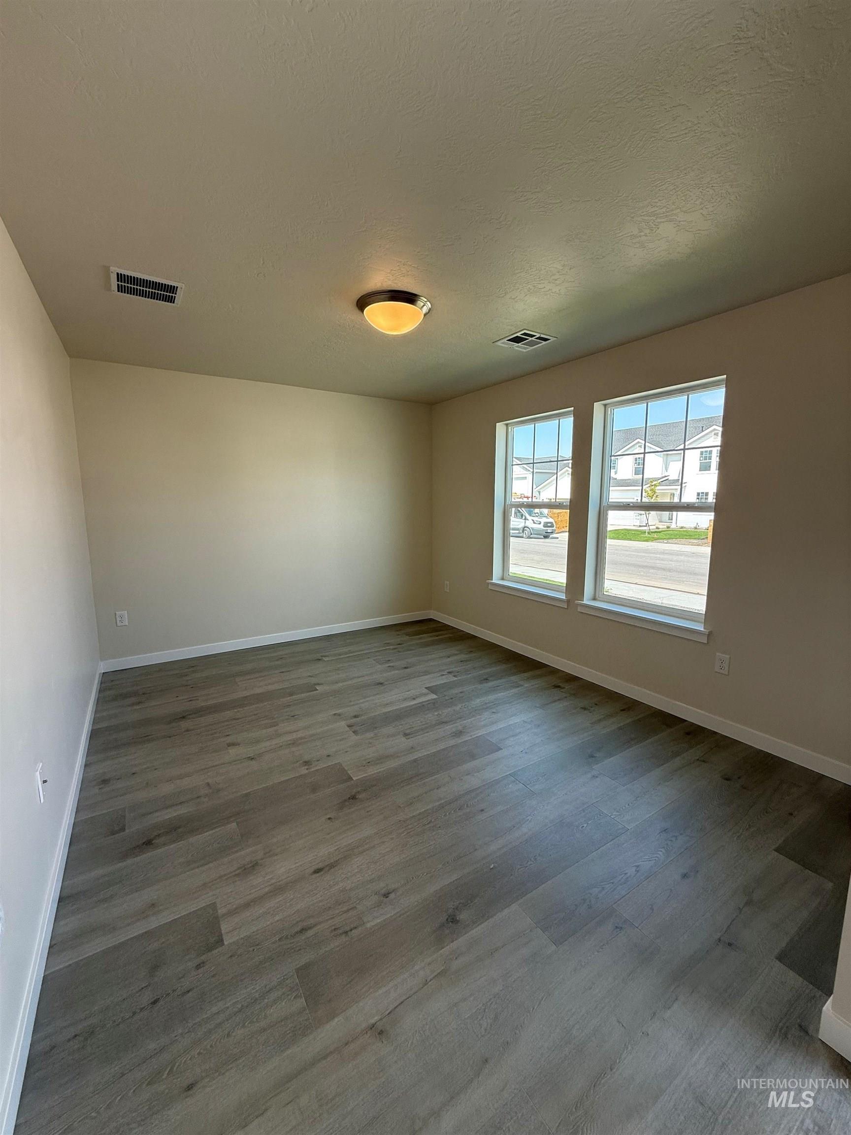 Empty room with a textured ceiling and light wood-style floors