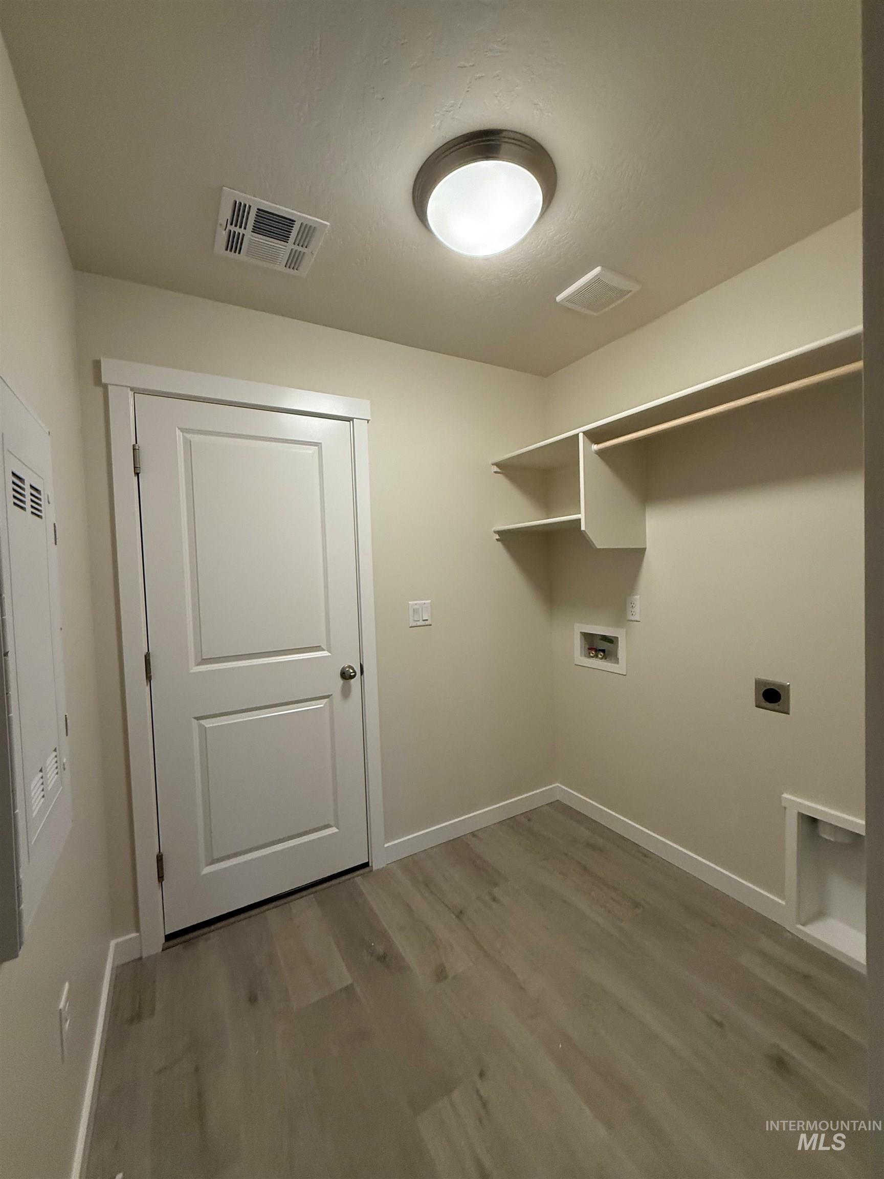 Washroom featuring hookup for a washing machine, hookup for an electric dryer, and light wood finished floors
