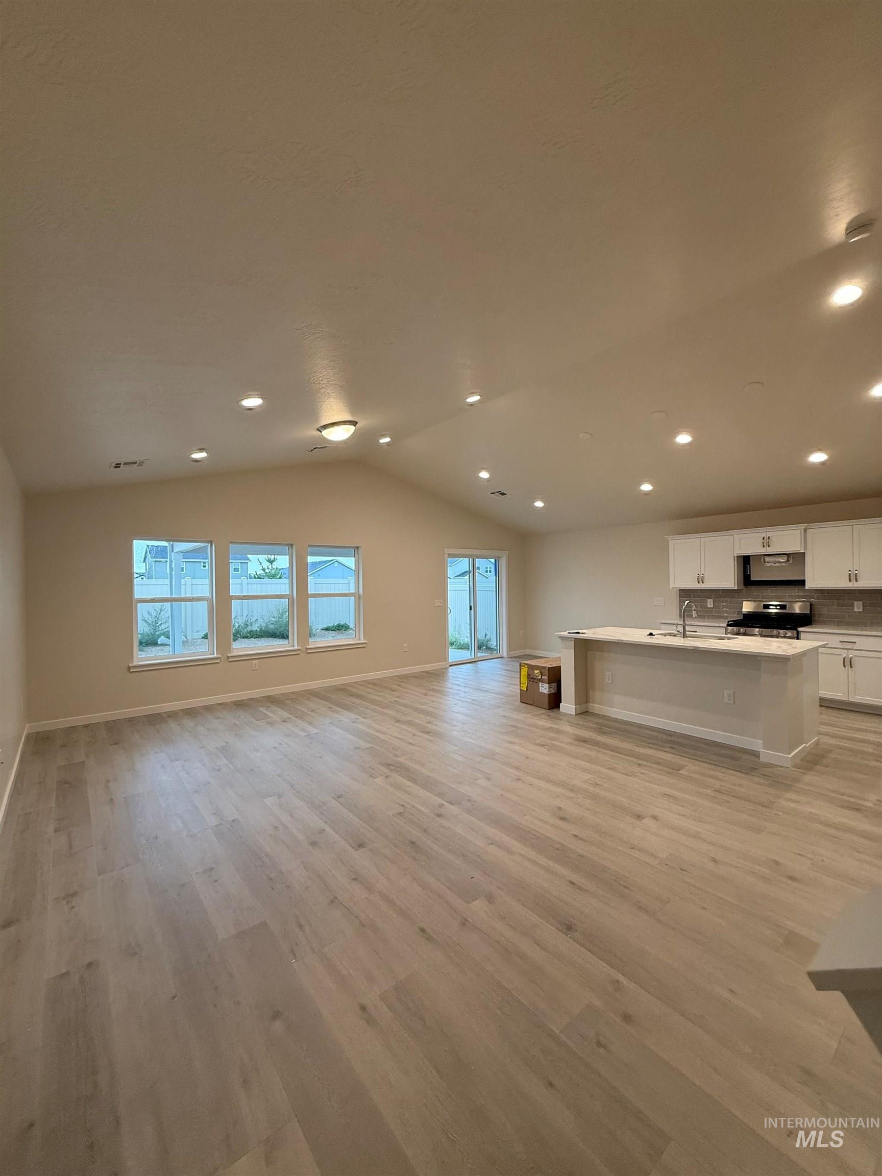 Unfurnished living room with vaulted ceiling, light wood finished floors, plenty of natural light, and recessed lighting