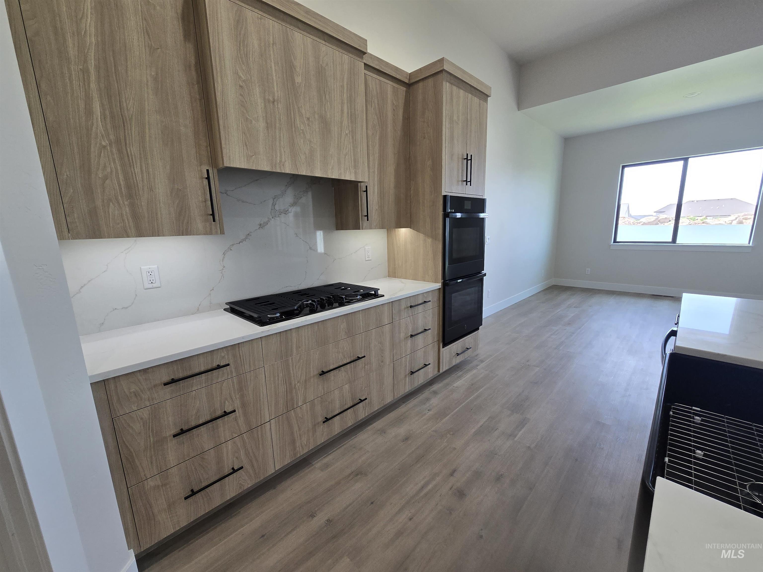 Kitchen featuring modern cabinets, black appliances, and light brown cabinets