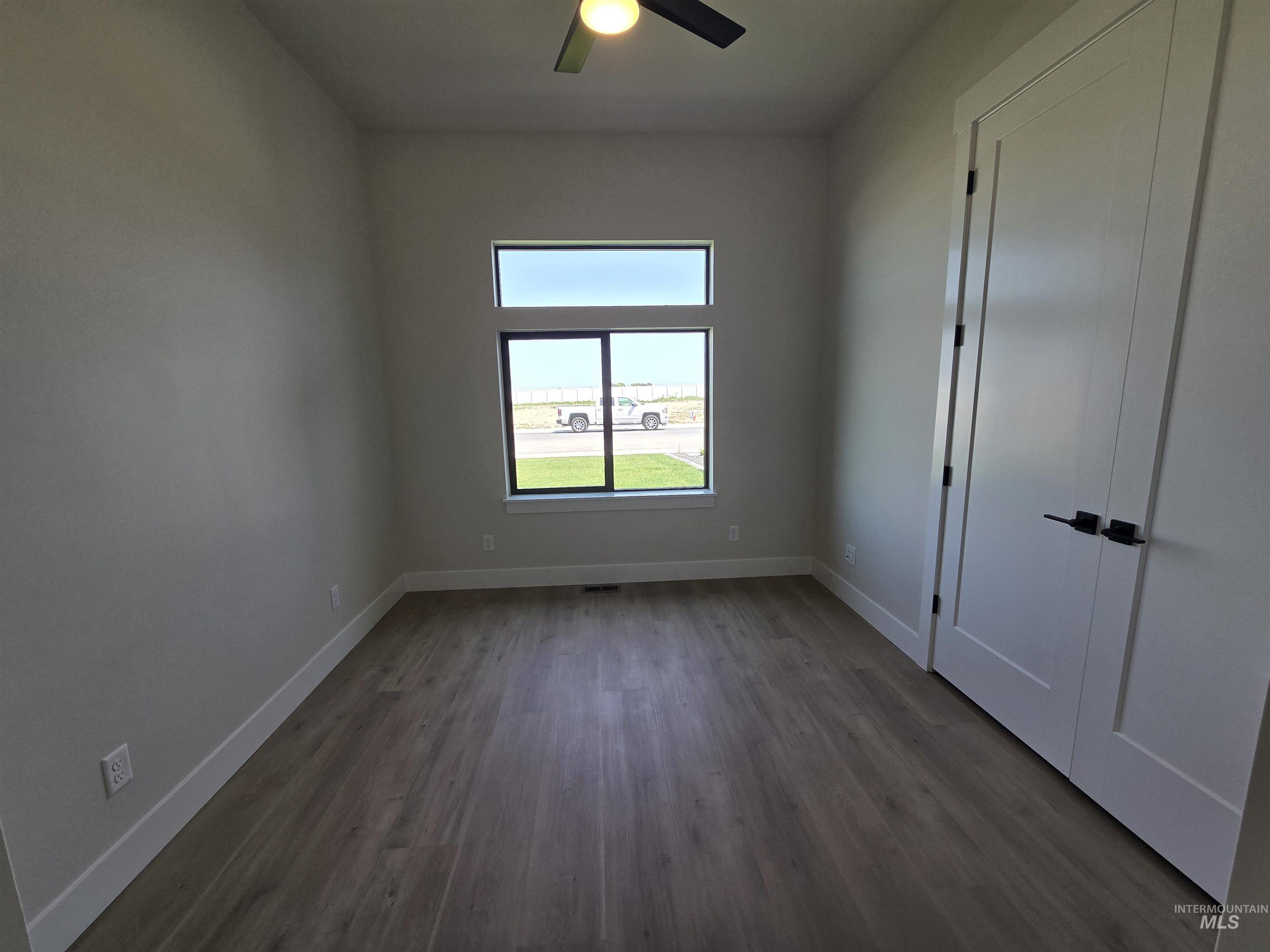 Spare room featuring dark wood-type flooring and ceiling fan