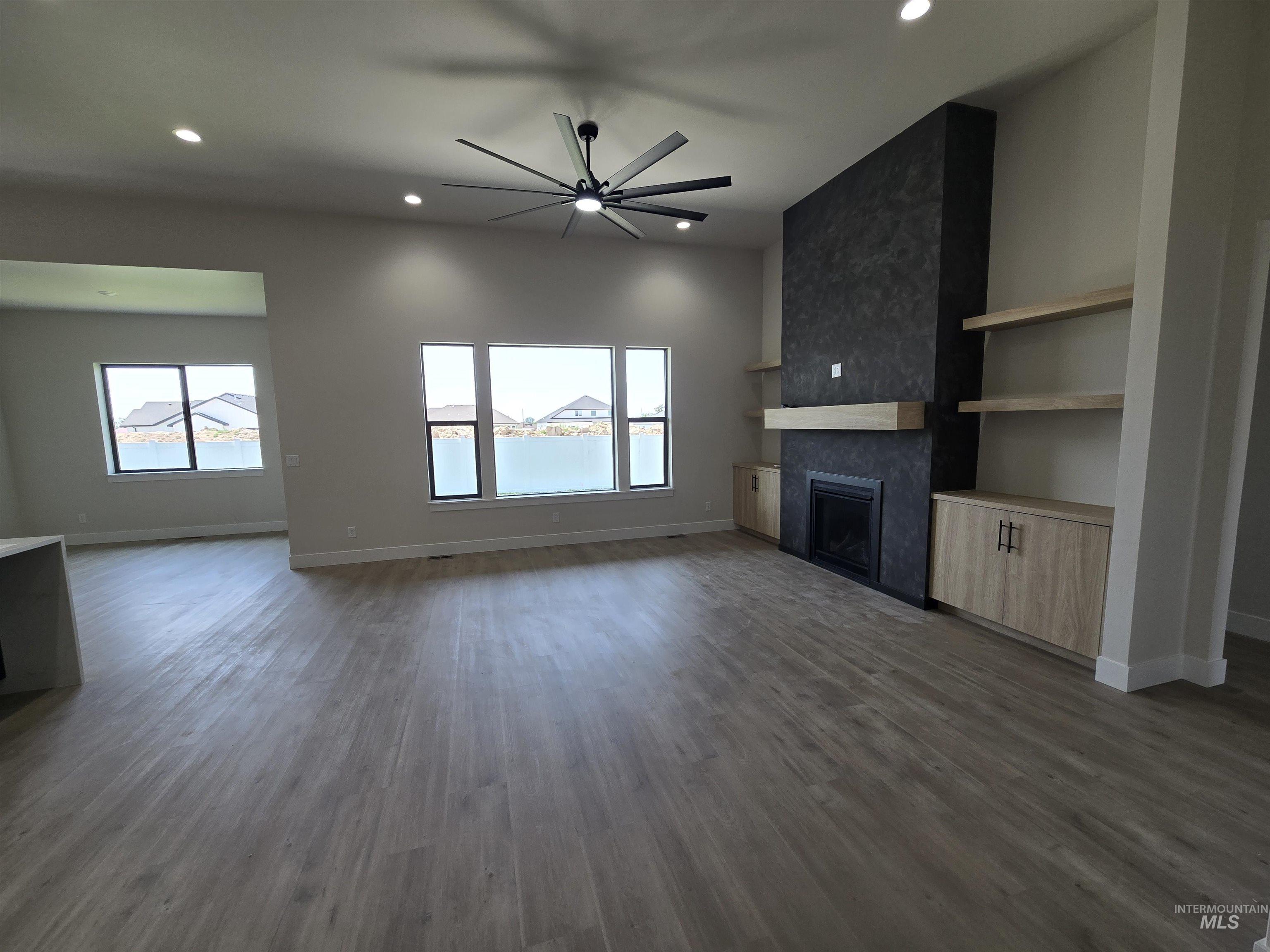 Unfurnished living room featuring dark wood finished floors, recessed lighting, a tile fireplace, and ceiling fan