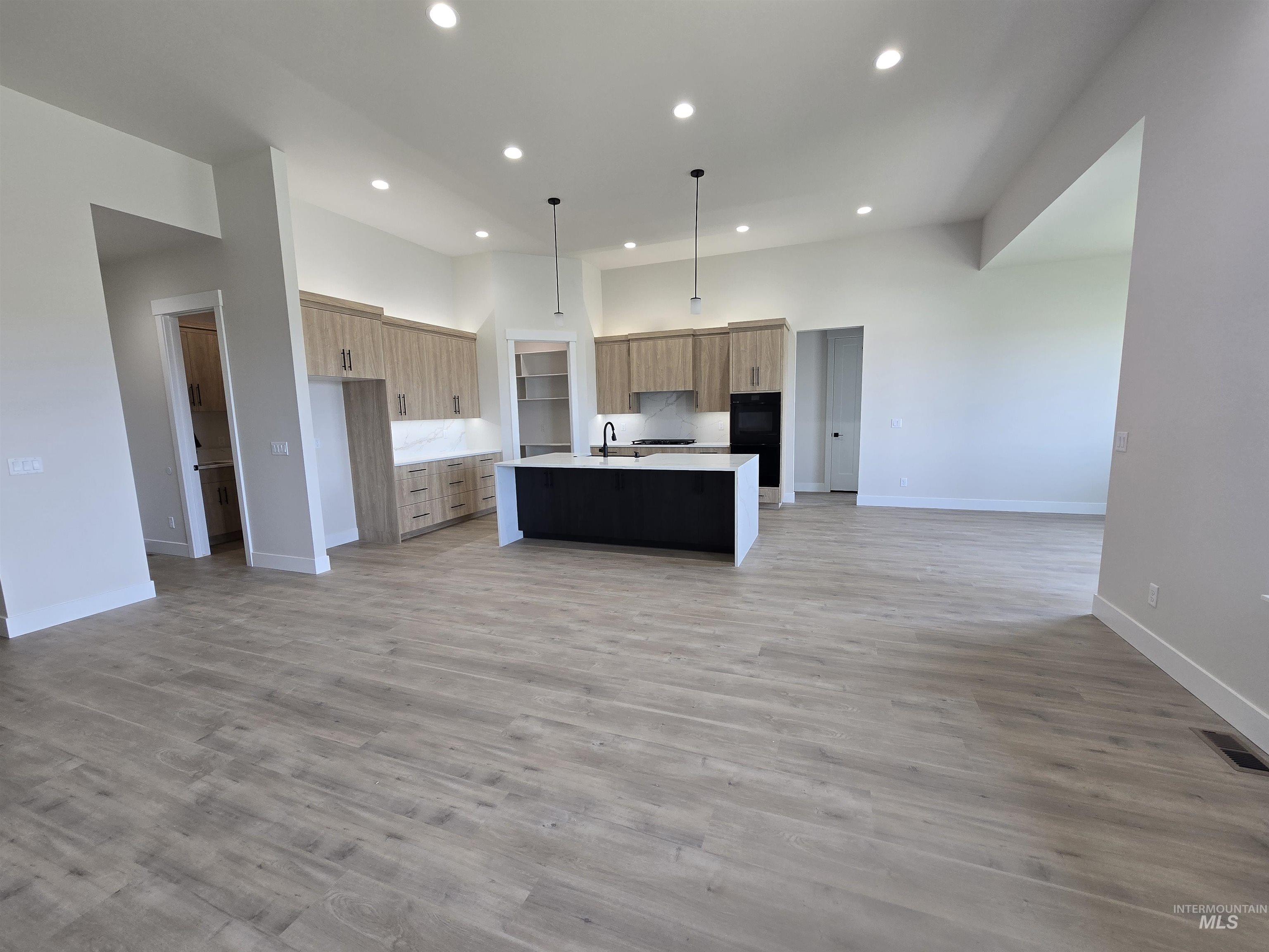 Kitchen featuring open floor plan, recessed lighting, modern cabinets, a kitchen island with sink, and light countertops