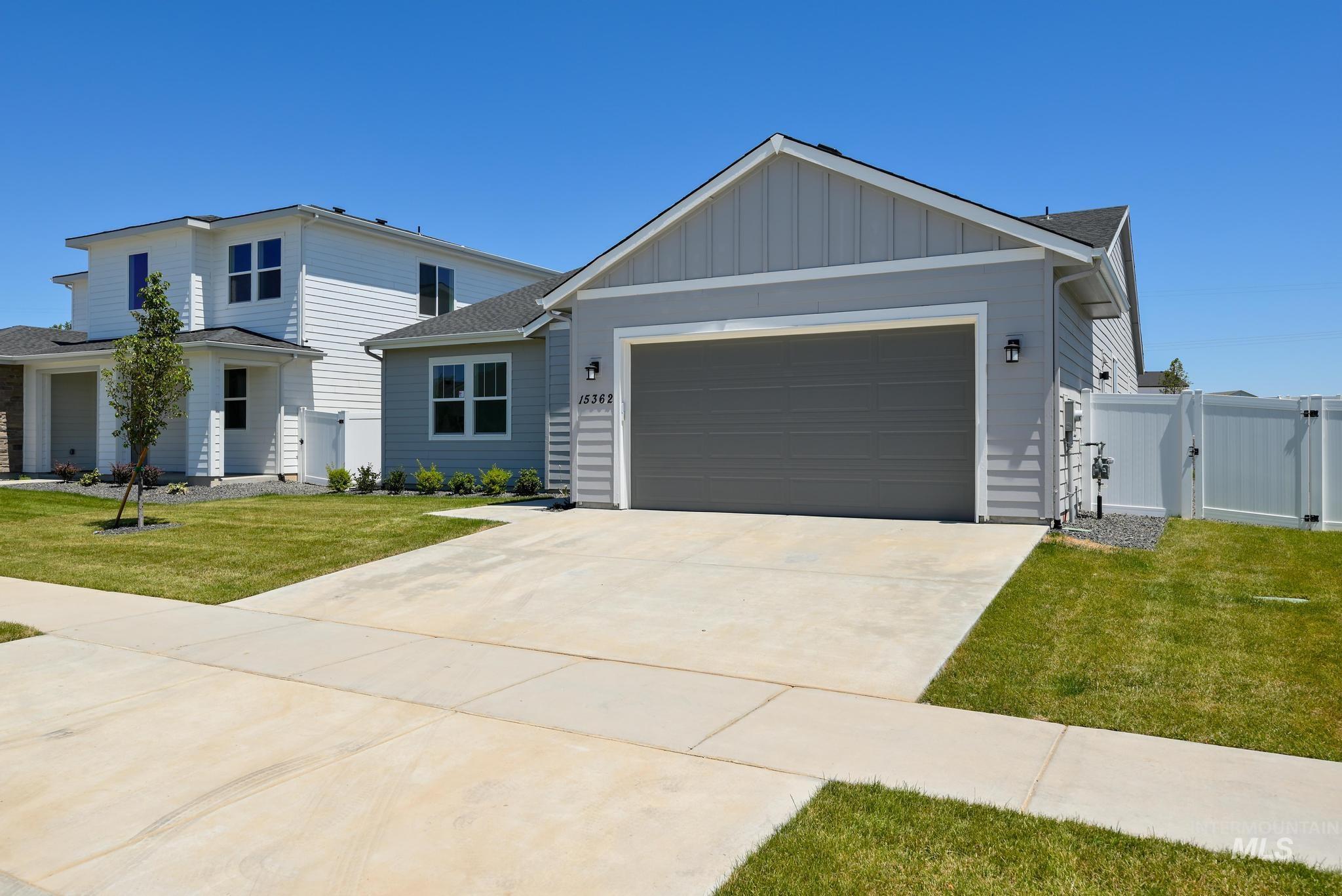 View of front facade with a gate, a garage, board and batten siding, and driveway