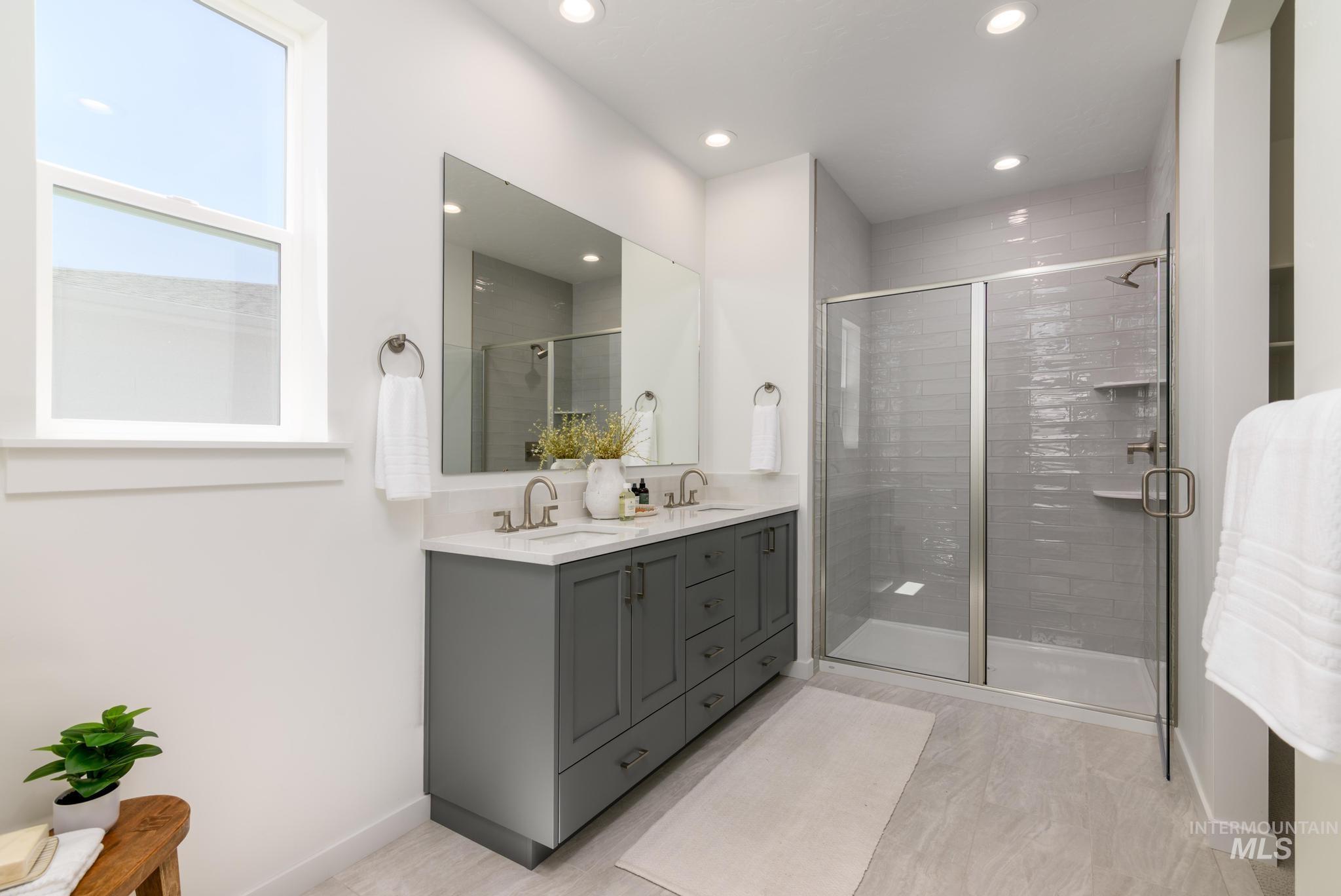 Bathroom featuring recessed lighting, double vanity, and a shower stall