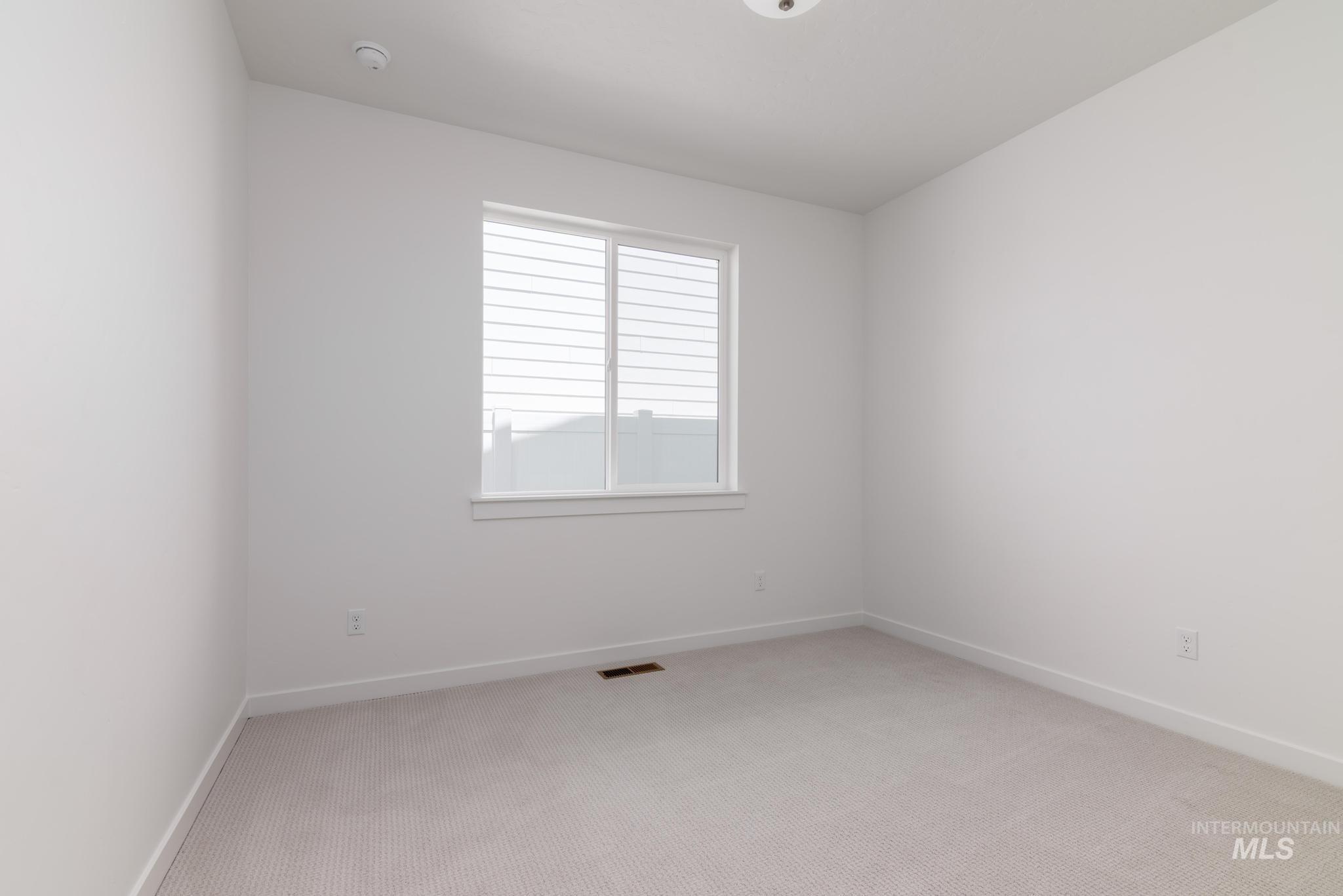 Unfurnished room with light colored carpet and a smoke detector