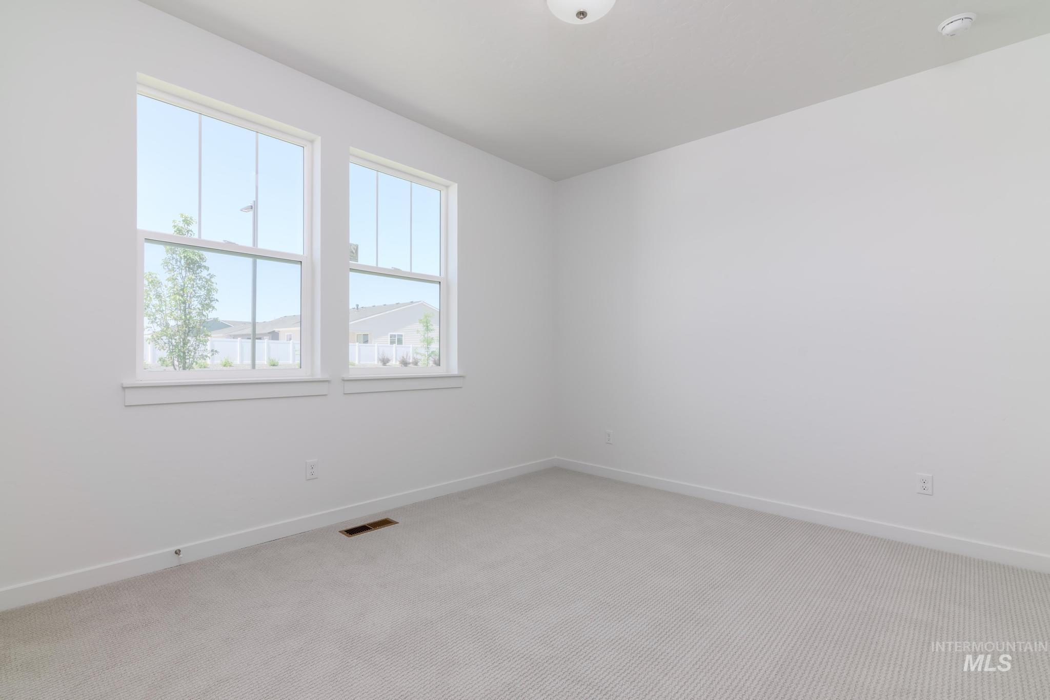 Unfurnished room with a smoke detector and light colored carpet