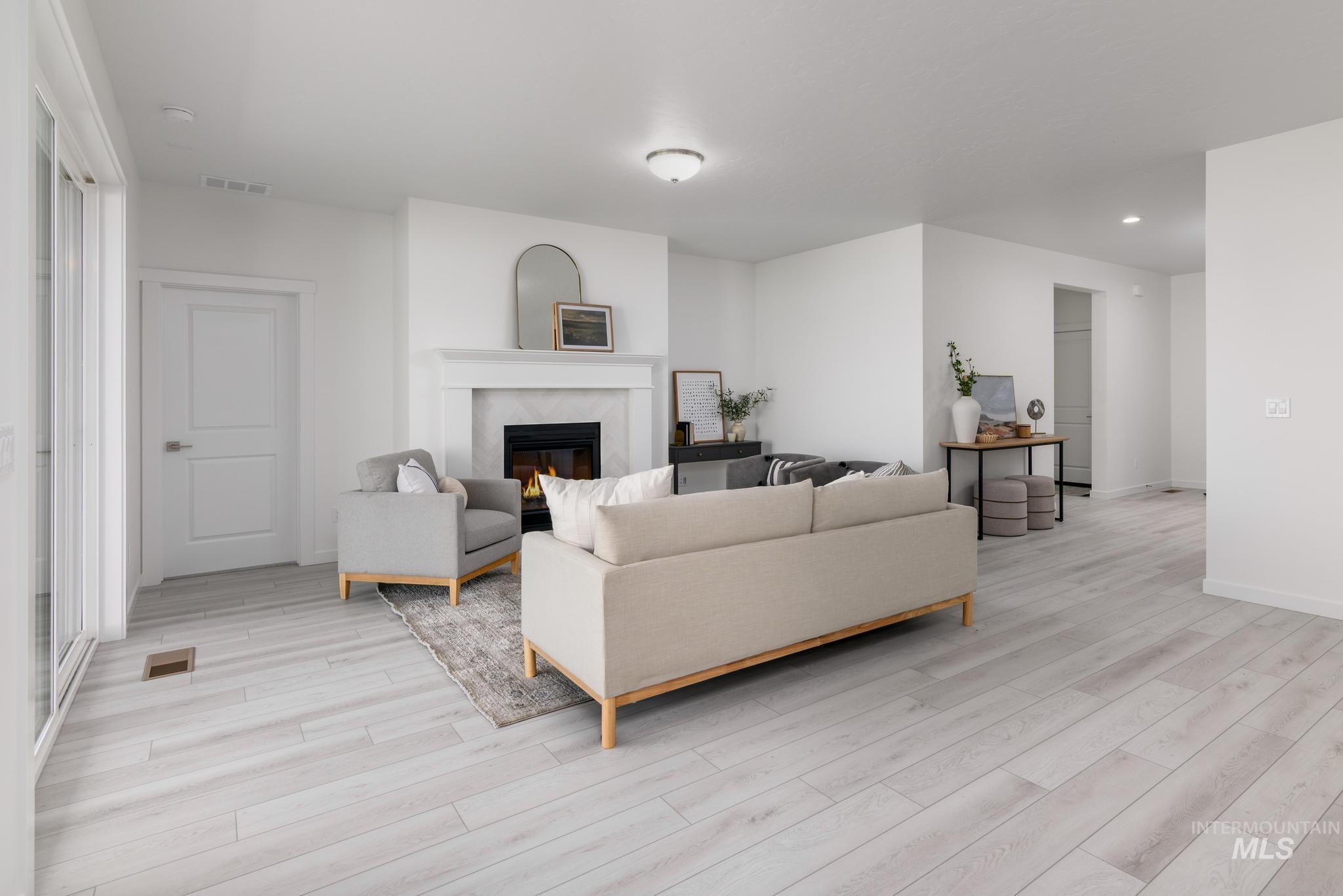 Living area with light wood-type flooring, a high end fireplace, recessed lighting, and plenty of natural light
