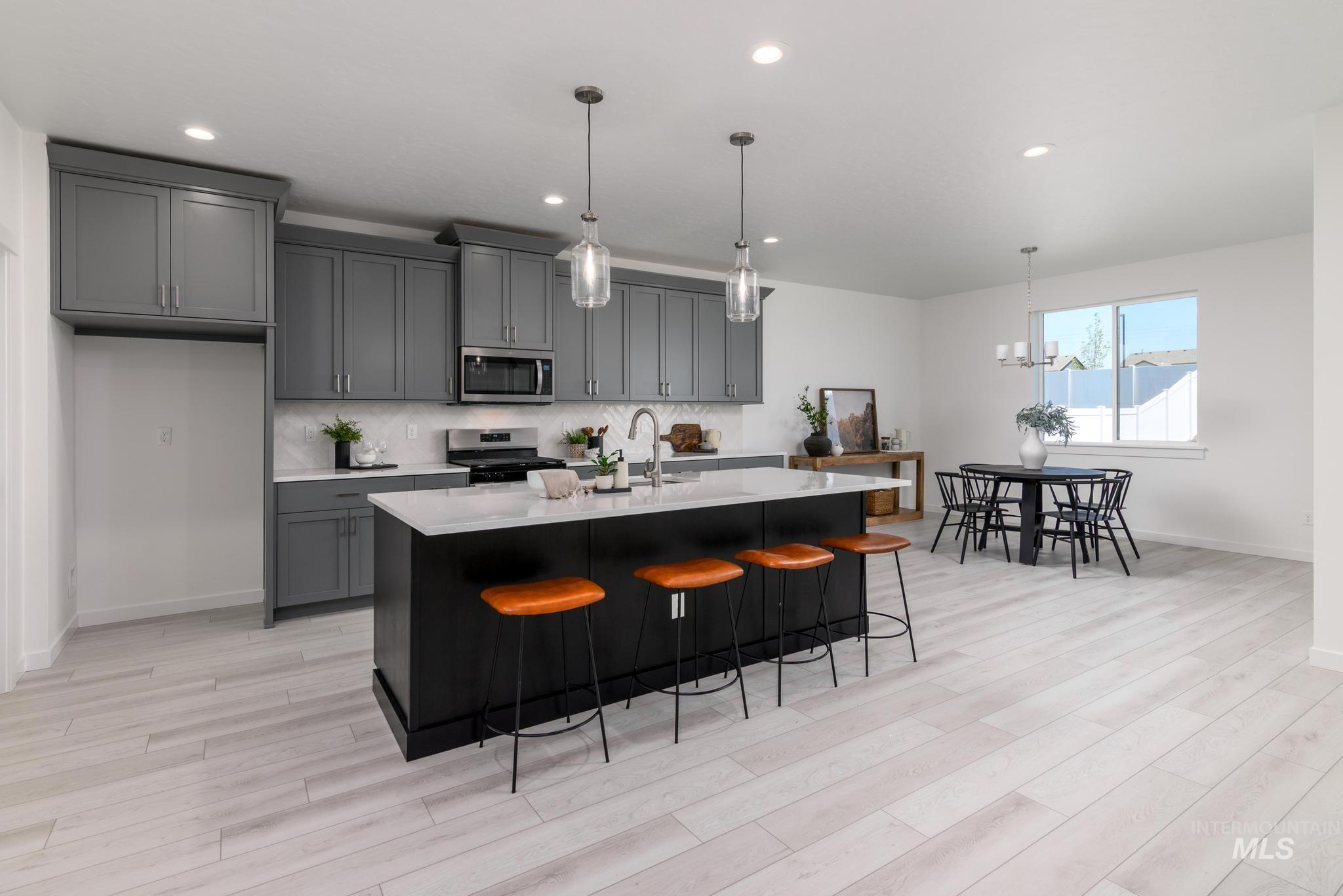 Kitchen featuring stainless steel microwave, electric range oven, light countertops, light wood-style floors, and gray cabinets