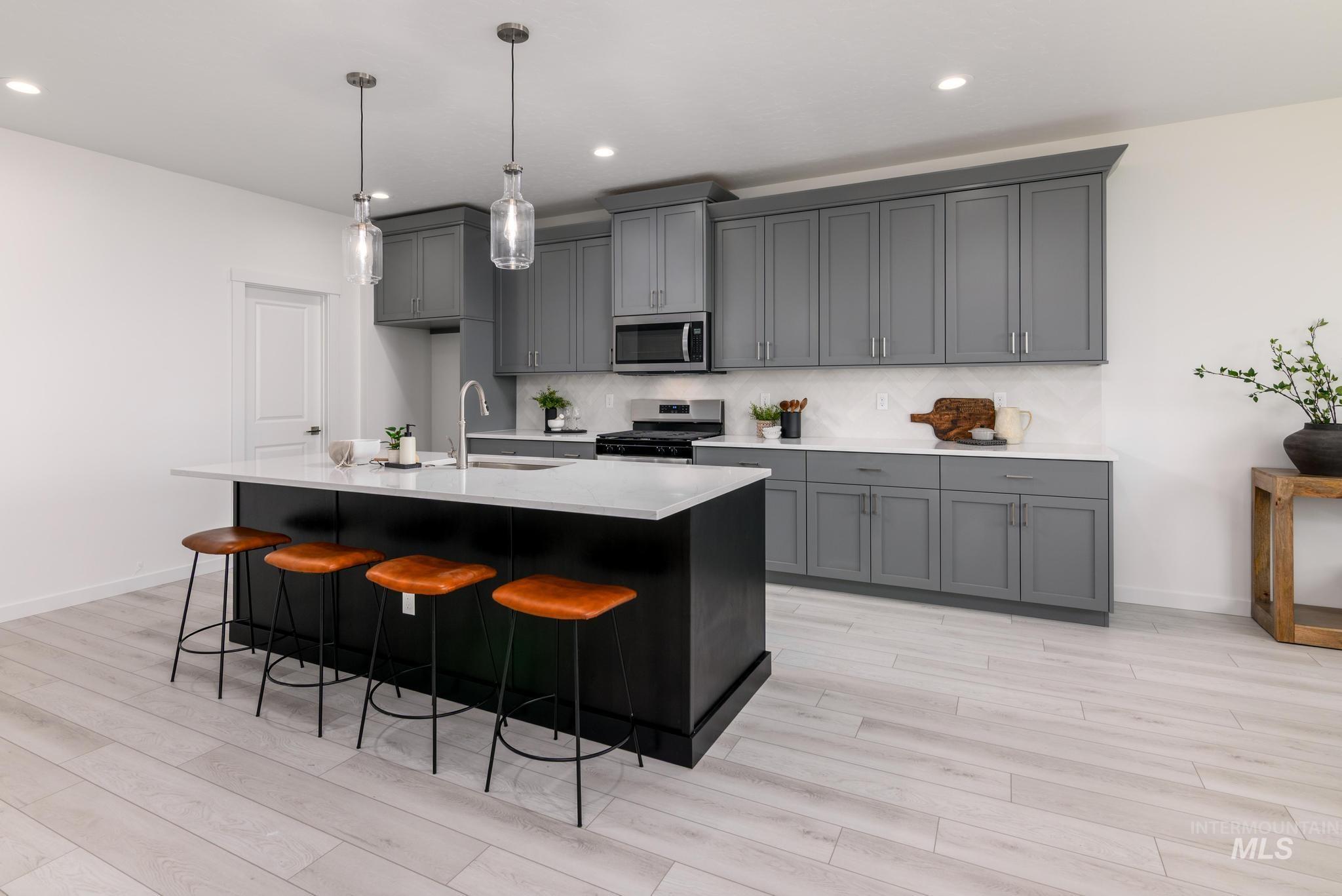 Kitchen featuring stainless steel appliances, gray cabinetry, light wood-type flooring, and recessed lighting