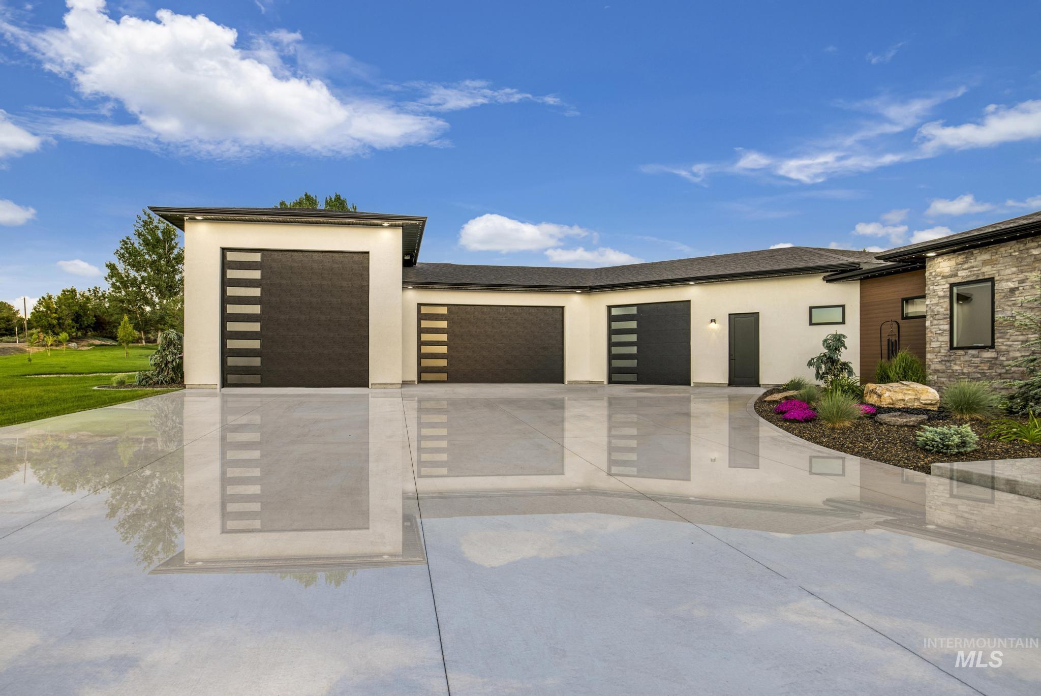 Contemporary house featuring a garage, stucco siding, driveway, and stone siding