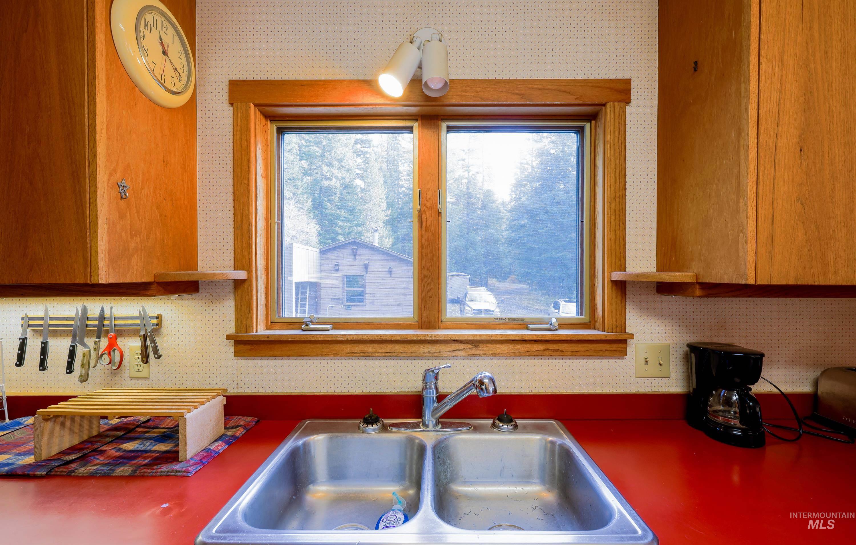 Kitchen featuring wallpapered walls and brown cabinetry