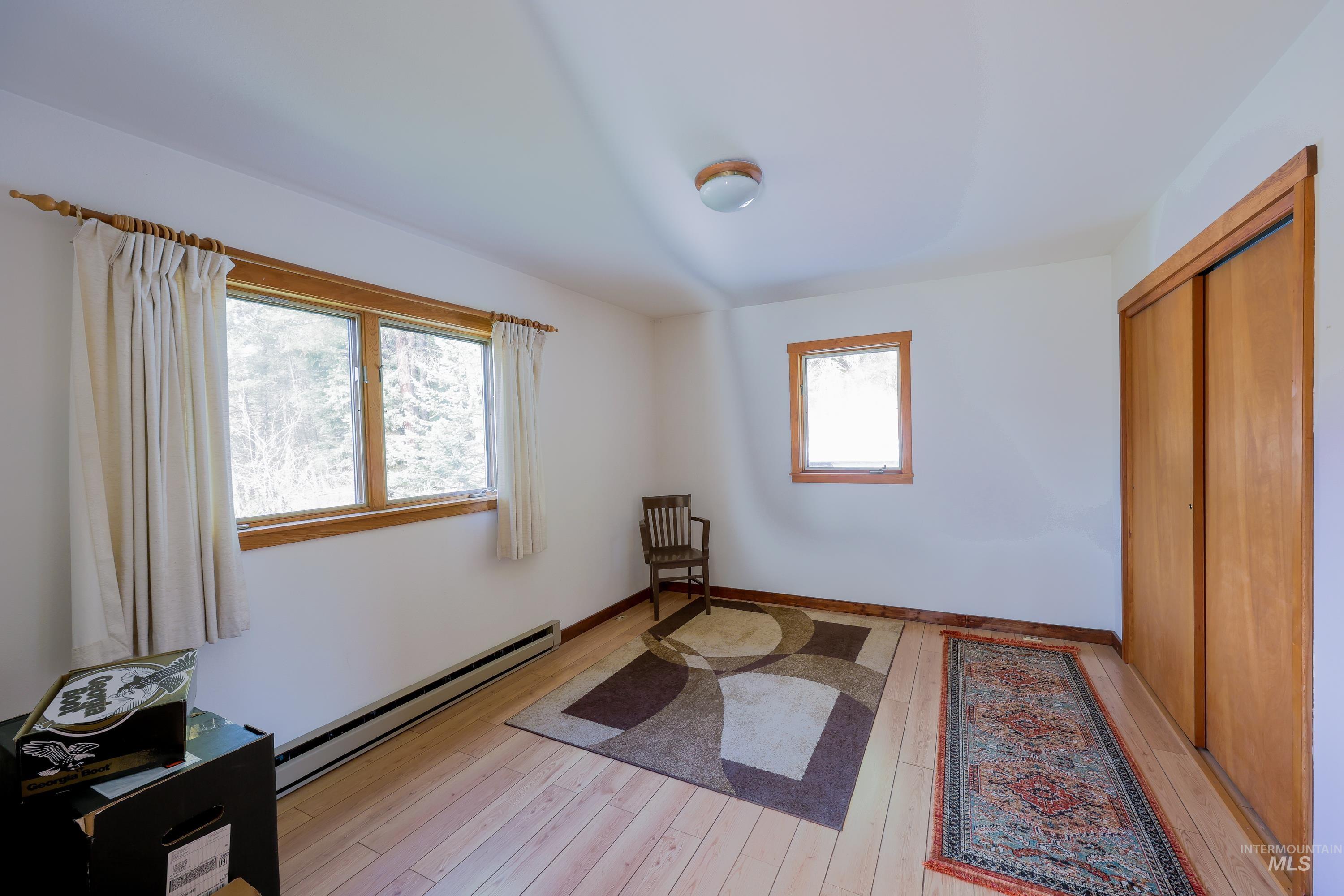 Bedroom featuring a baseboard heating unit, light wood-style floors, and a closet