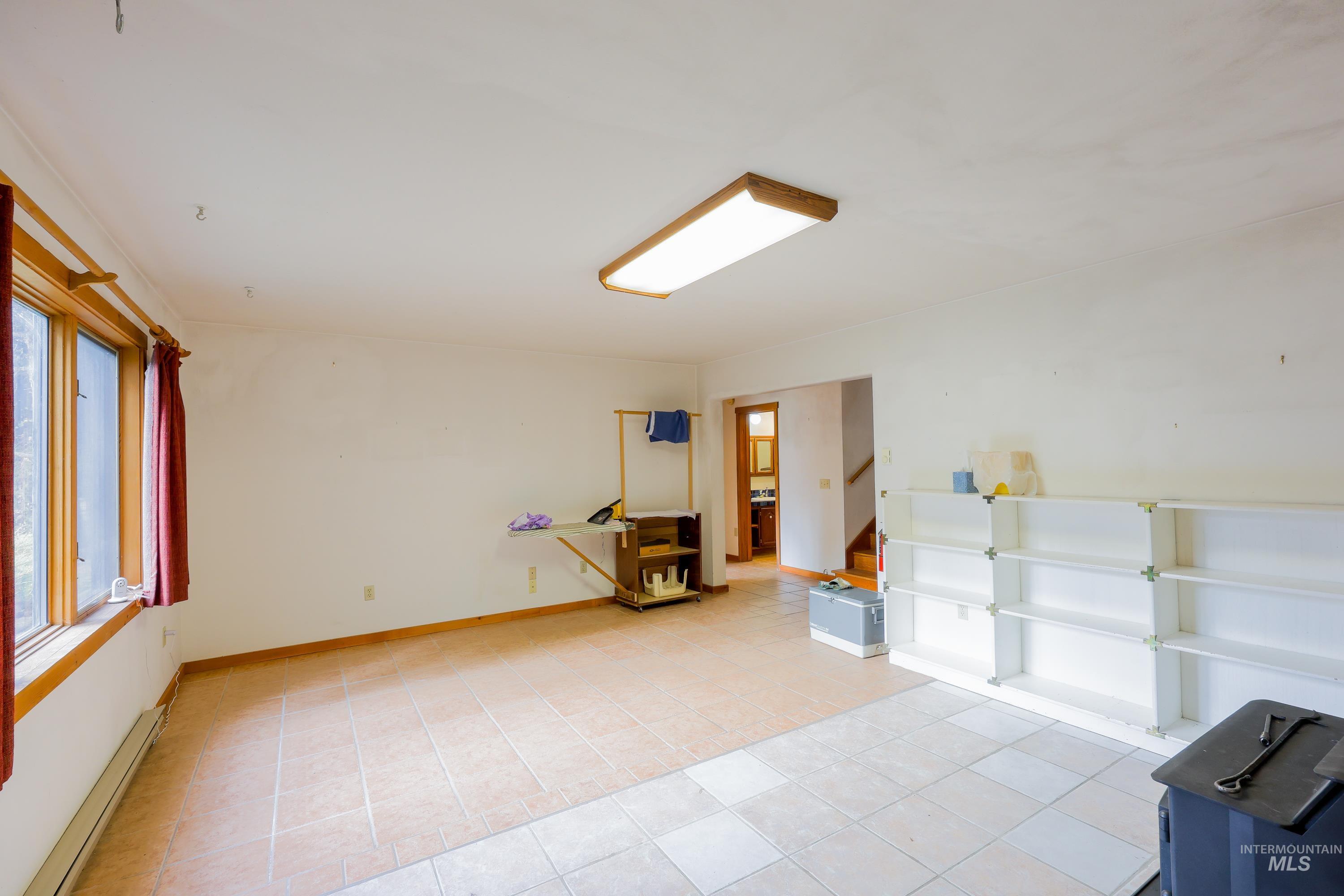 Empty room featuring a baseboard heating unit and light tile patterned flooring