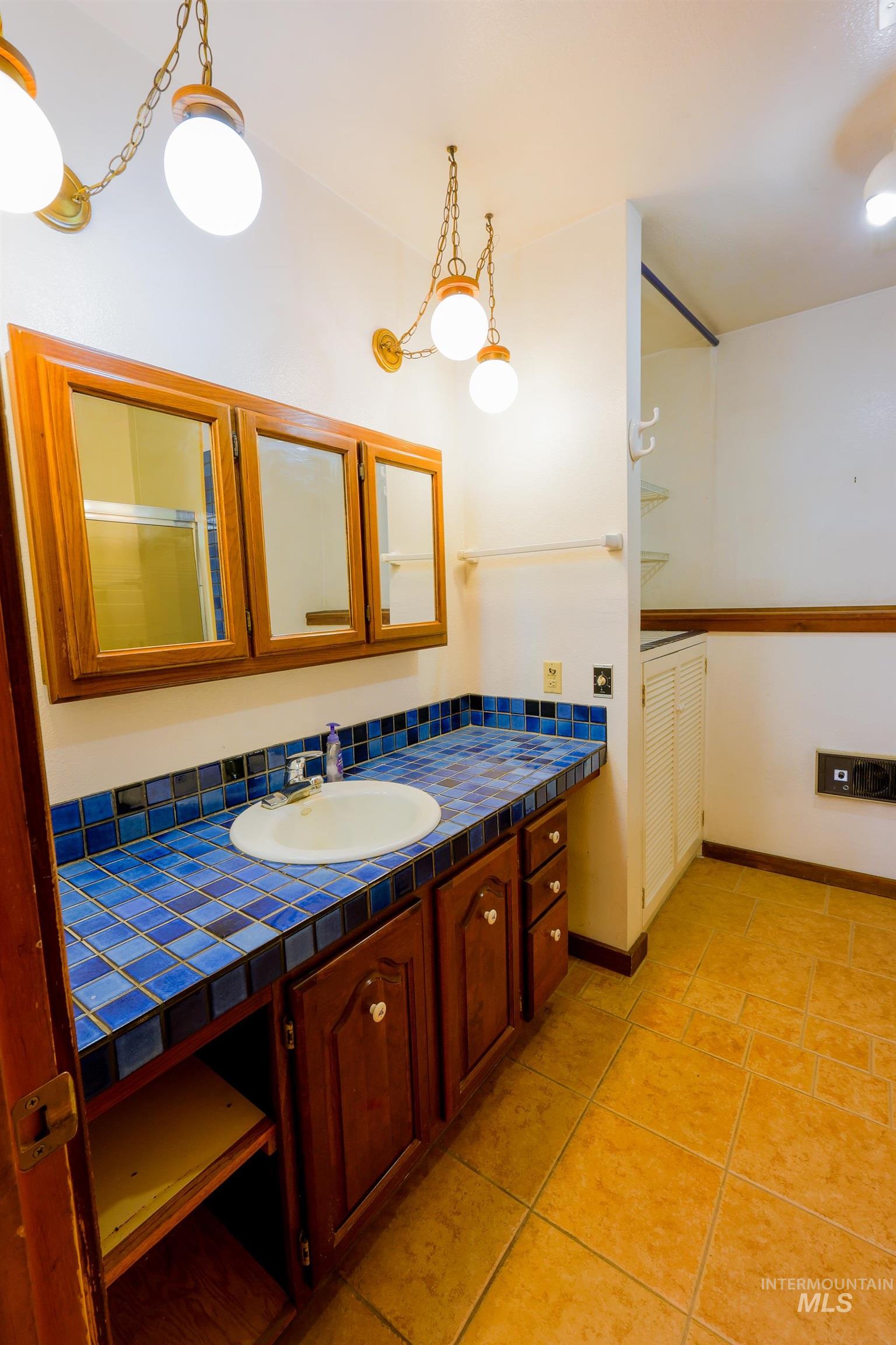 Bathroom with vanity, light tile patterned flooring, and a shower with shower door