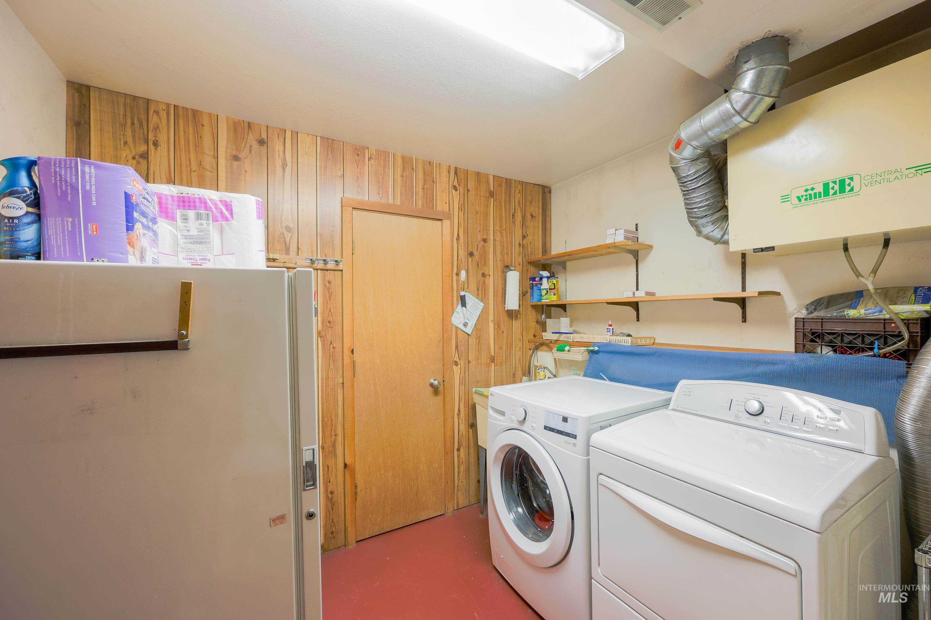 Washroom with wooden walls and separate washer and dryer