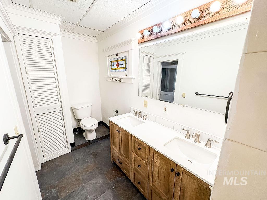 Bathroom featuring double vanity, stone finish flooring, a closet, and a drop ceiling