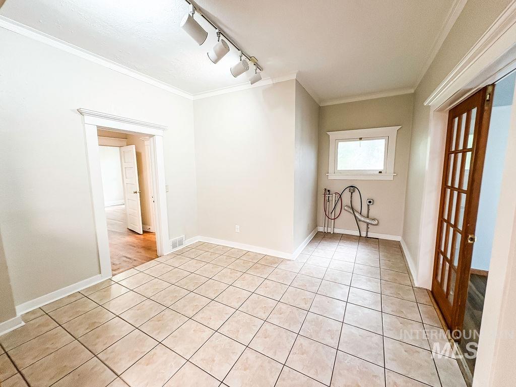 Unfurnished room featuring light tile patterned floors, crown molding, and track lighting