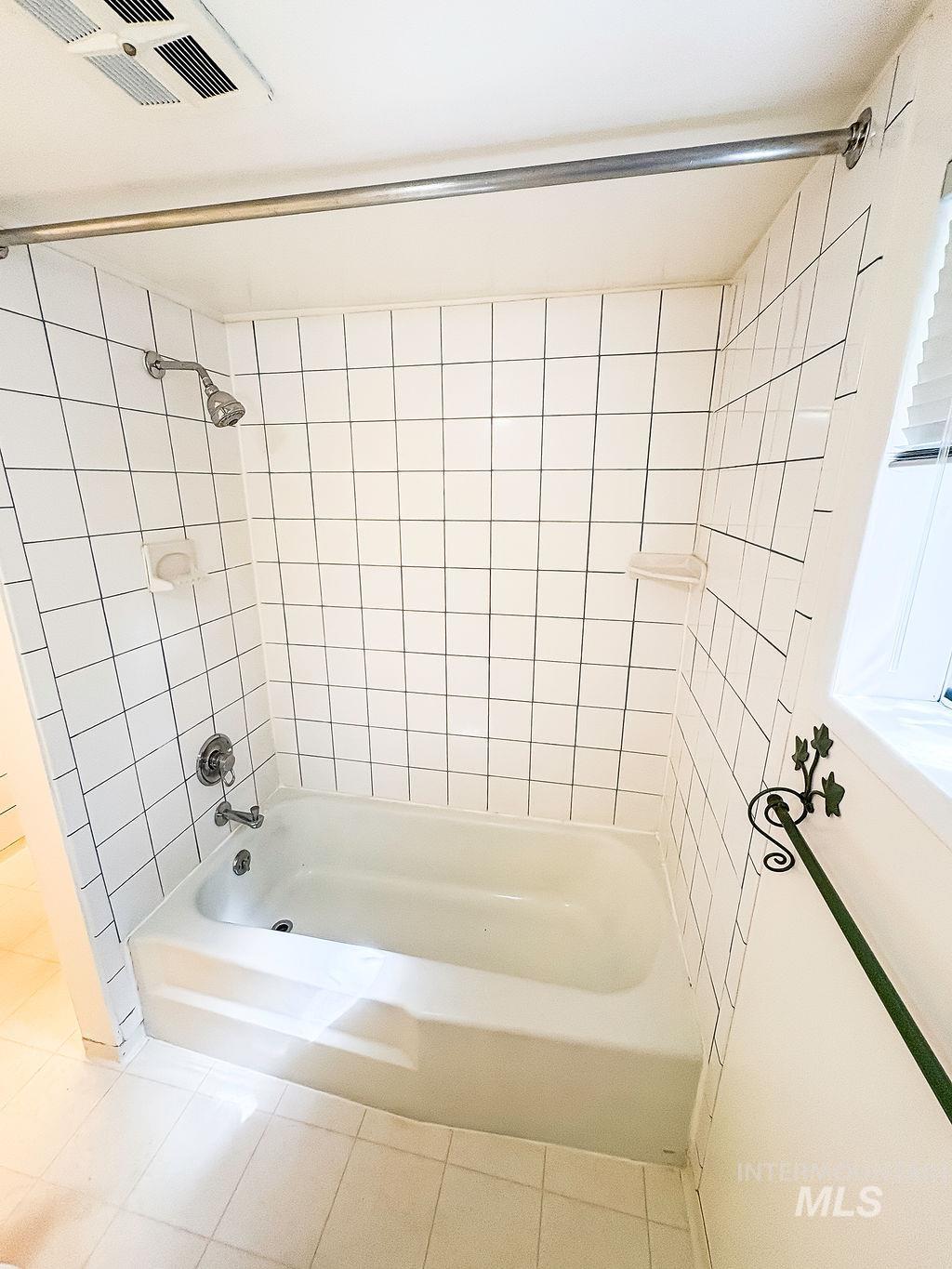 Bathroom with tile patterned floors and shower / tub combination