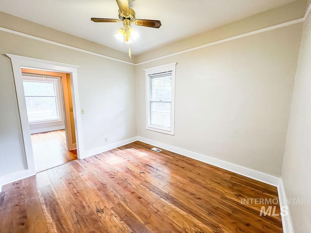 Empty room featuring light wood-style floors, healthy amount of natural light, and ceiling fan