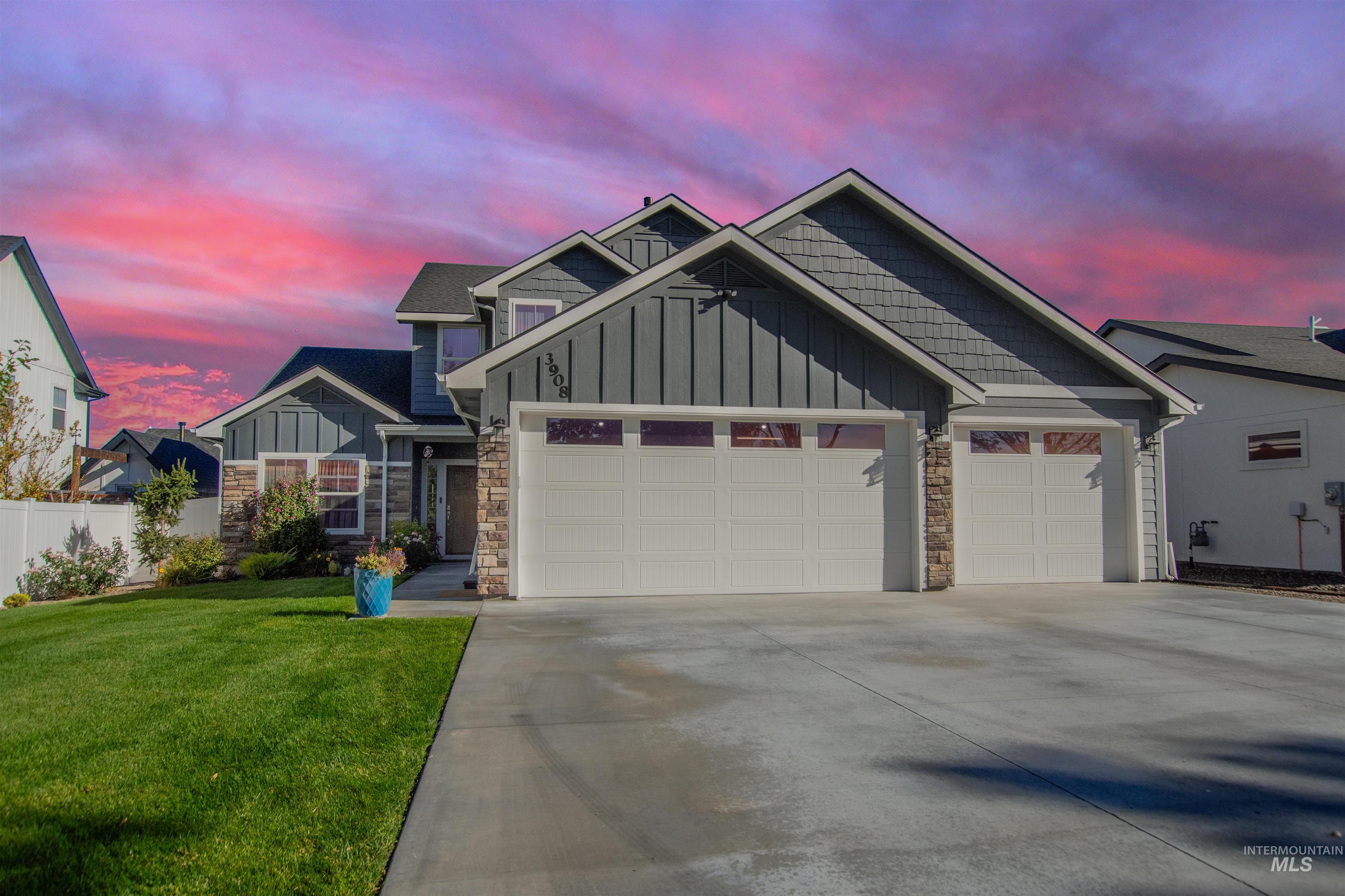 Craftsman-style home featuring stone siding, board and batten siding, an attached garage, and driveway