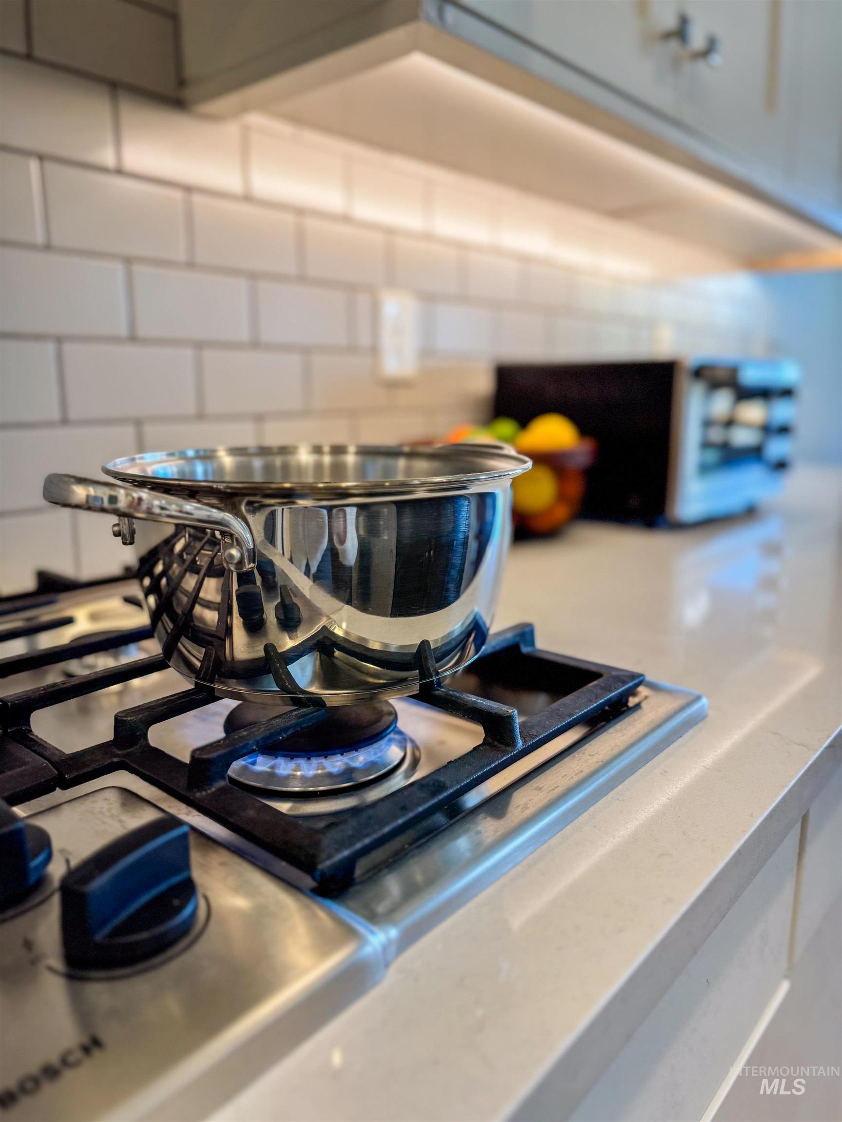 Kitchen view of stainless steel gas stovetop and light stone countertops