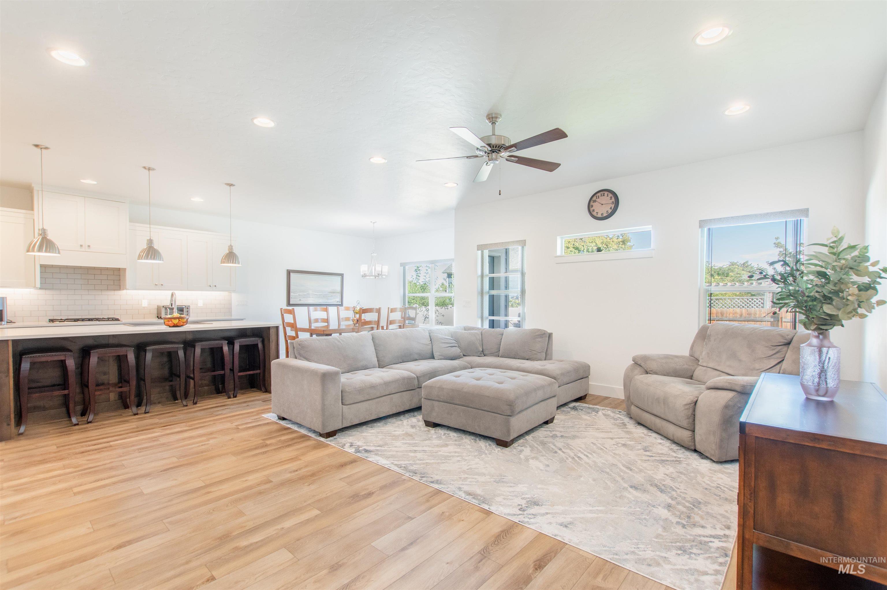 Living area with light wood finished floors, recessed lighting, ceiling fan, and a chandelier