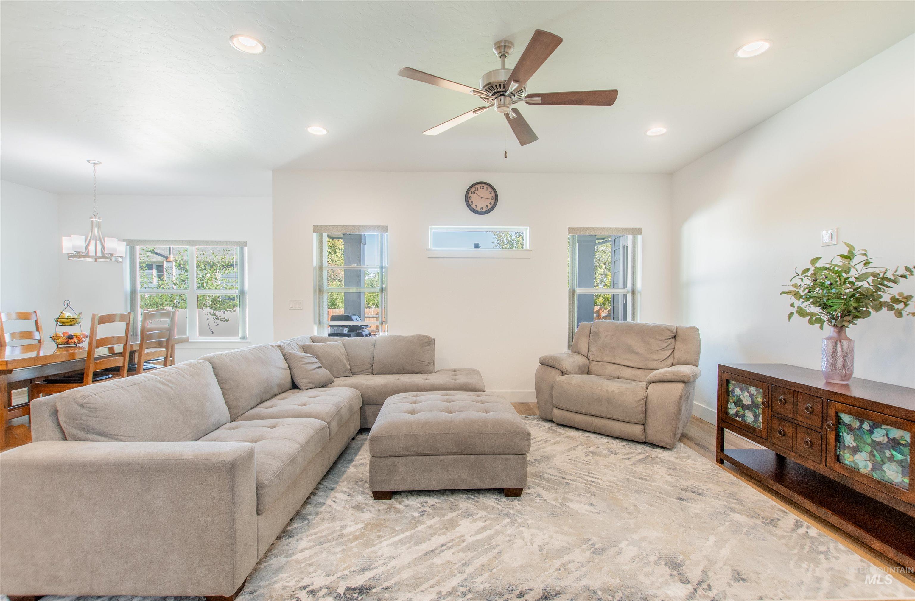 Living room featuring recessed lighting, wood finished floors, a ceiling fan, and a chandelier