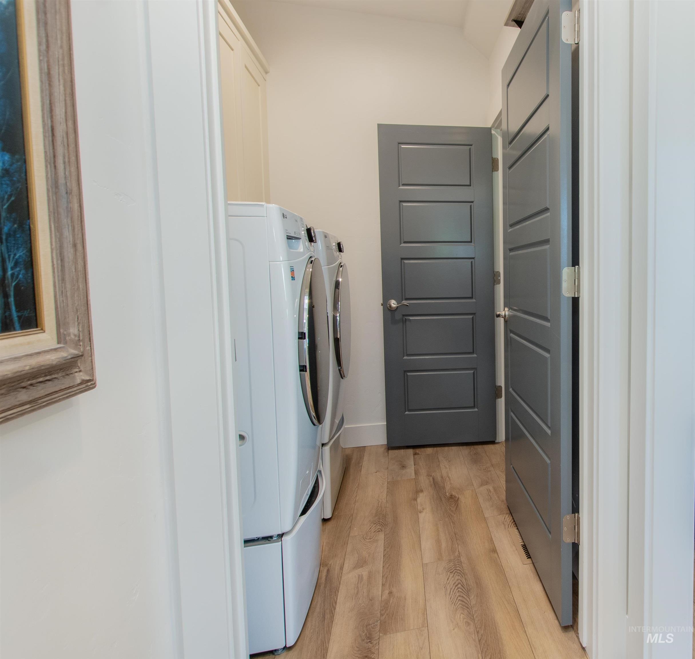 Washroom with light wood finished floors and washer and clothes dryer