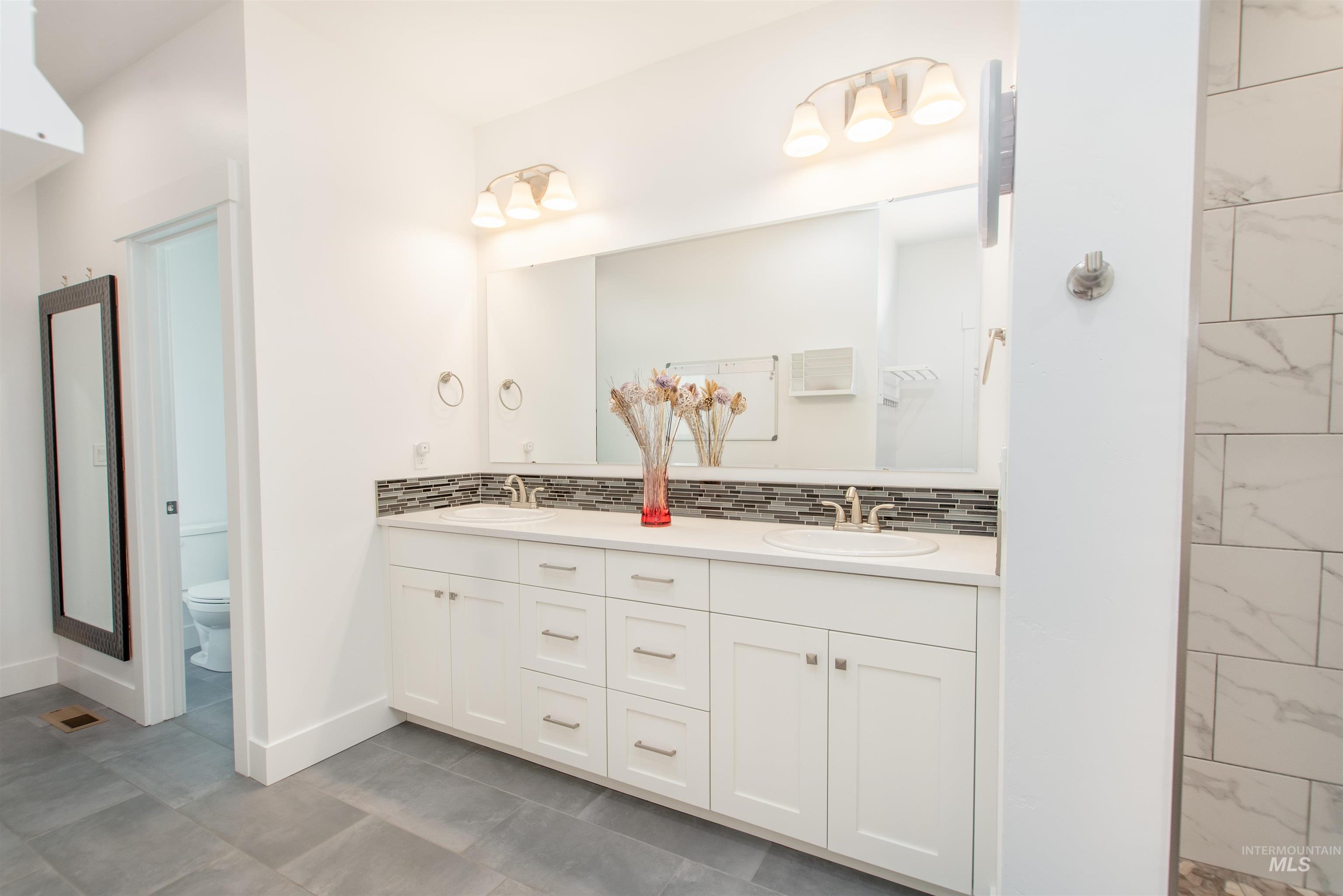 Full bath with decorative backsplash and double vanity