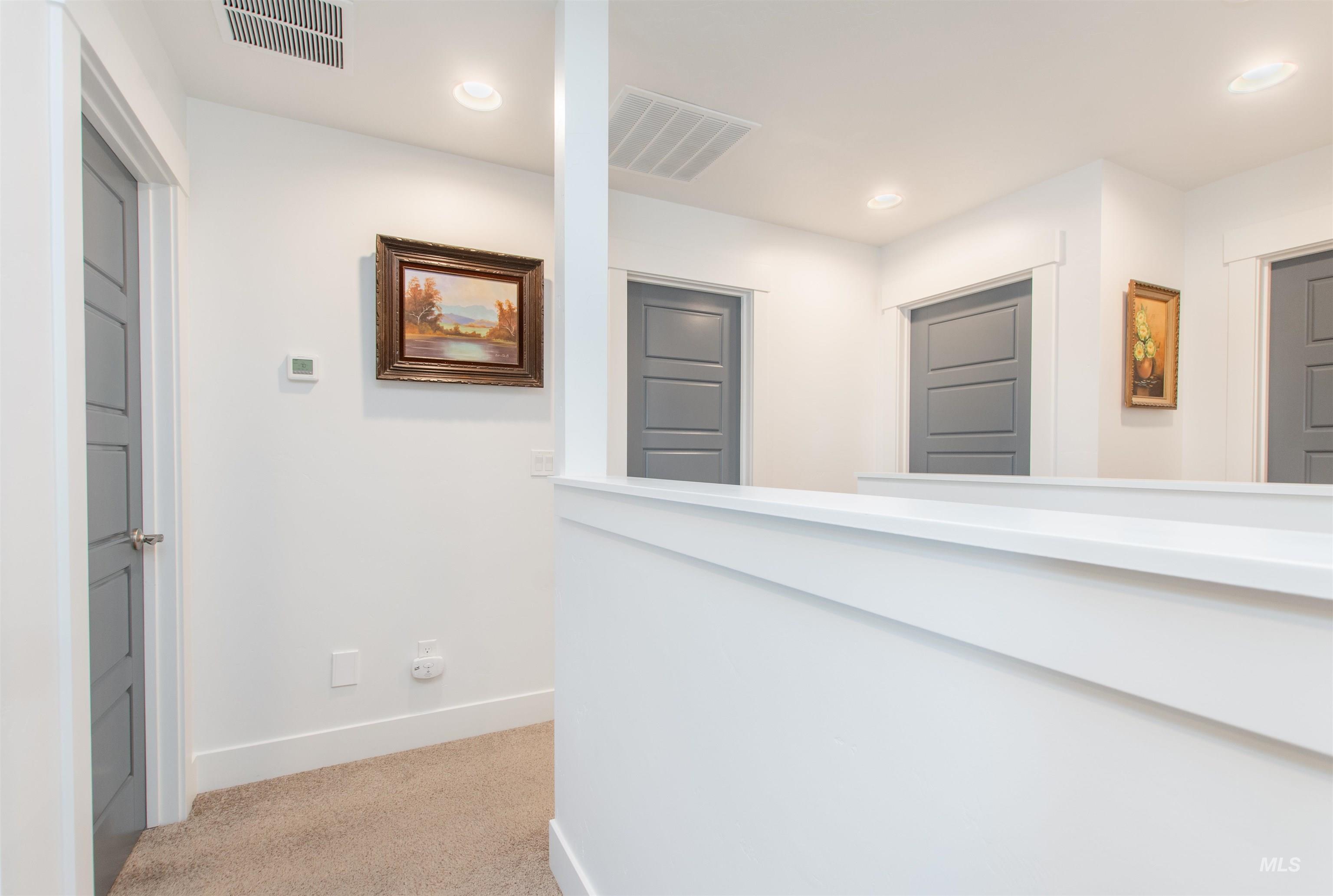 Corridor with light colored carpet and recessed lighting