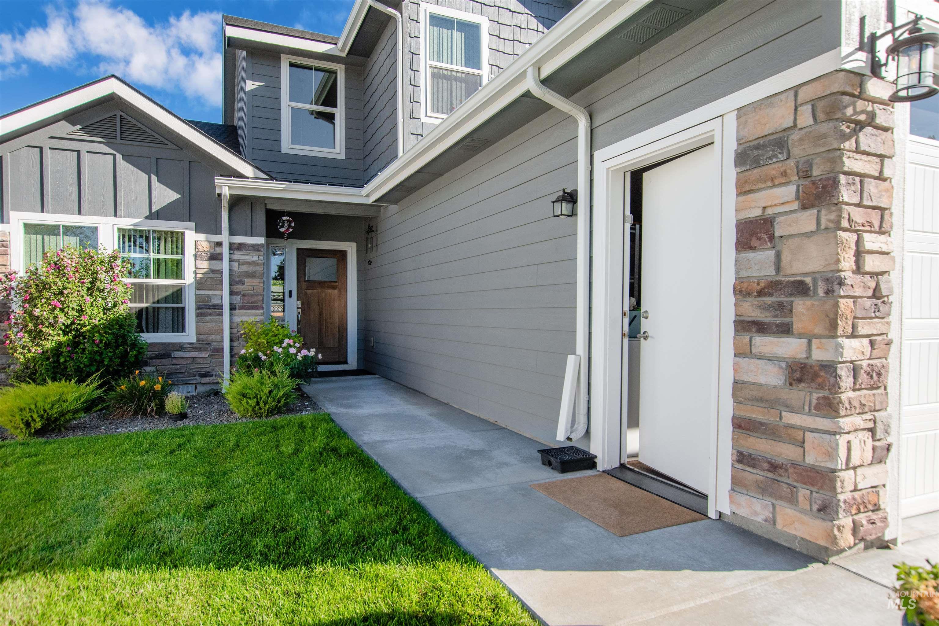Property entrance featuring a garage, a yard, and stone siding