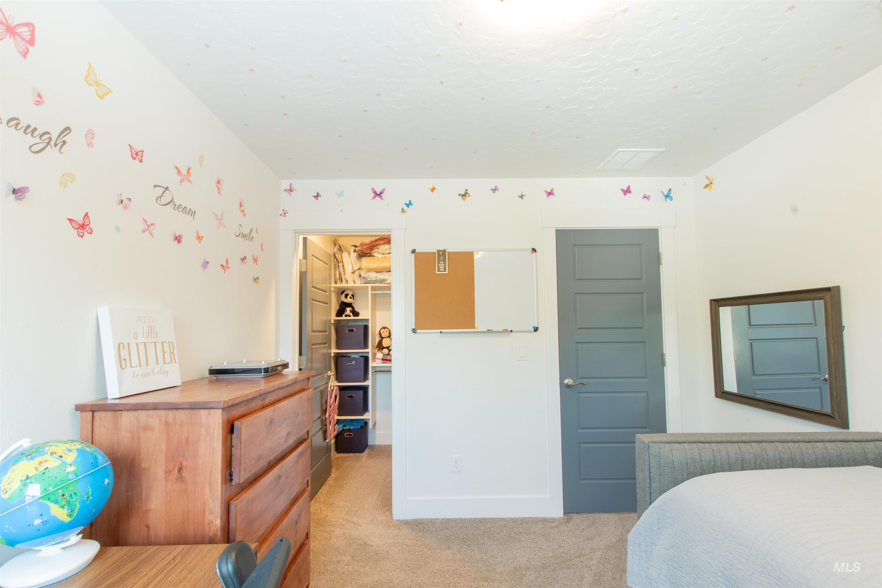 Bedroom with light colored carpet and a walk in closet