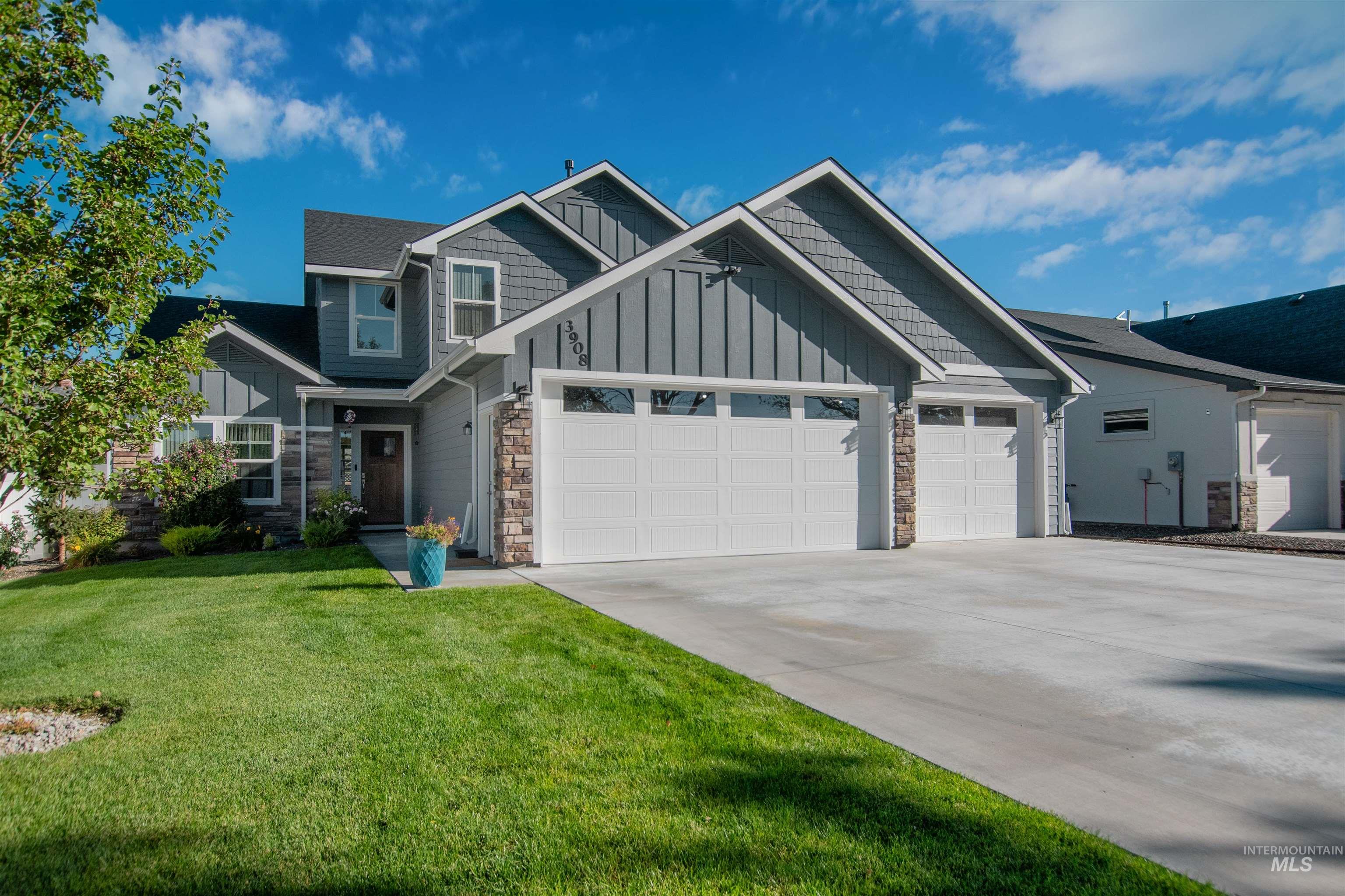 Craftsman-style home featuring stone siding, a garage, board and batten siding, driveway, and a front yard