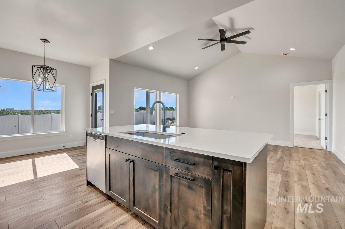 Kitchen featuring light wood-style floors, light countertops, hanging light fixtures, a ceiling fan, and stainless steel dishwasher