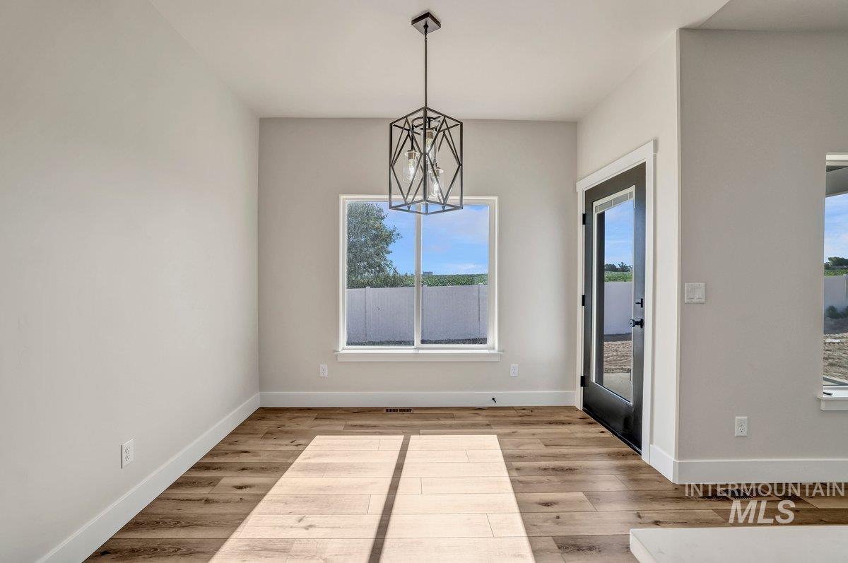 Unfurnished dining area featuring healthy amount of natural light, wood finished floors, and a chandelier