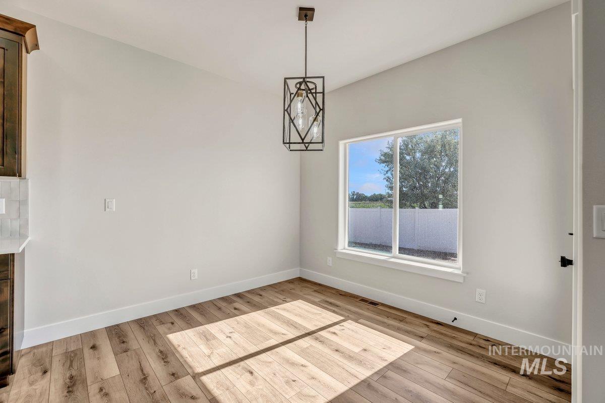 Unfurnished dining area featuring light wood-style flooring and baseboards
