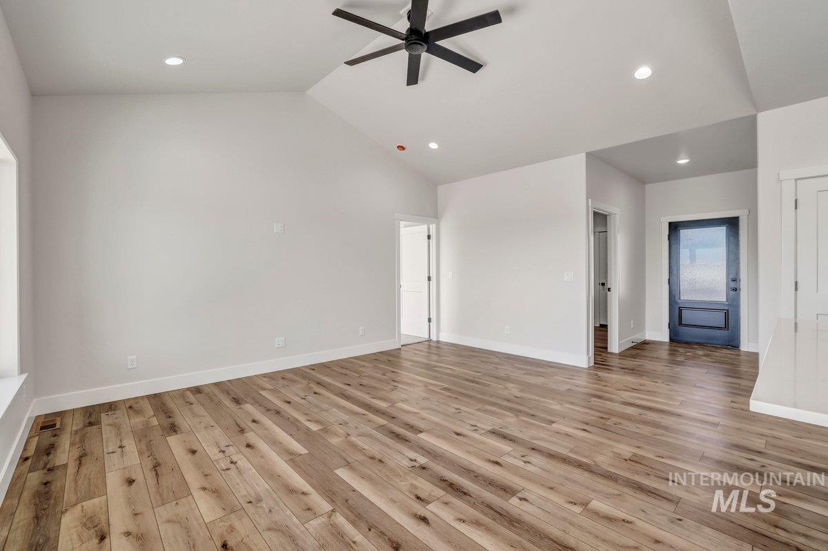 Unfurnished living room featuring ceiling fan, light wood-style floors, lofted ceiling, and recessed lighting