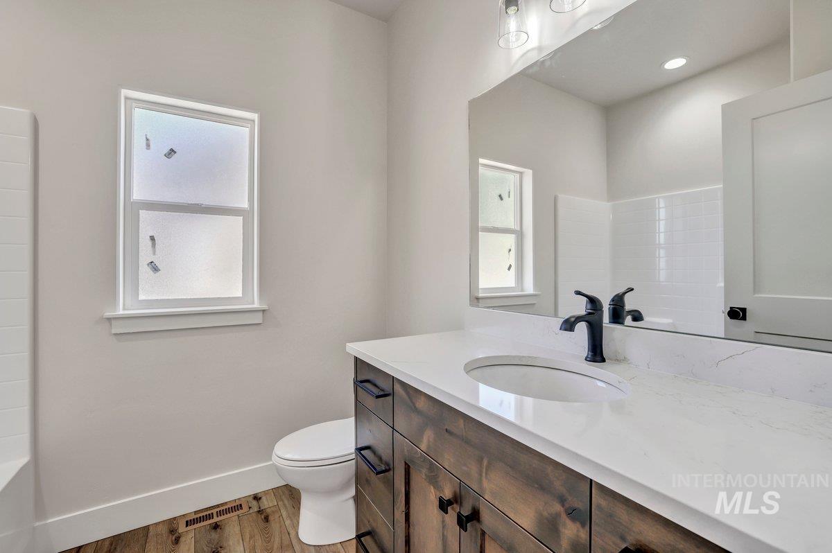 Full bath with vanity, wood finished floors, a bath, and a shower