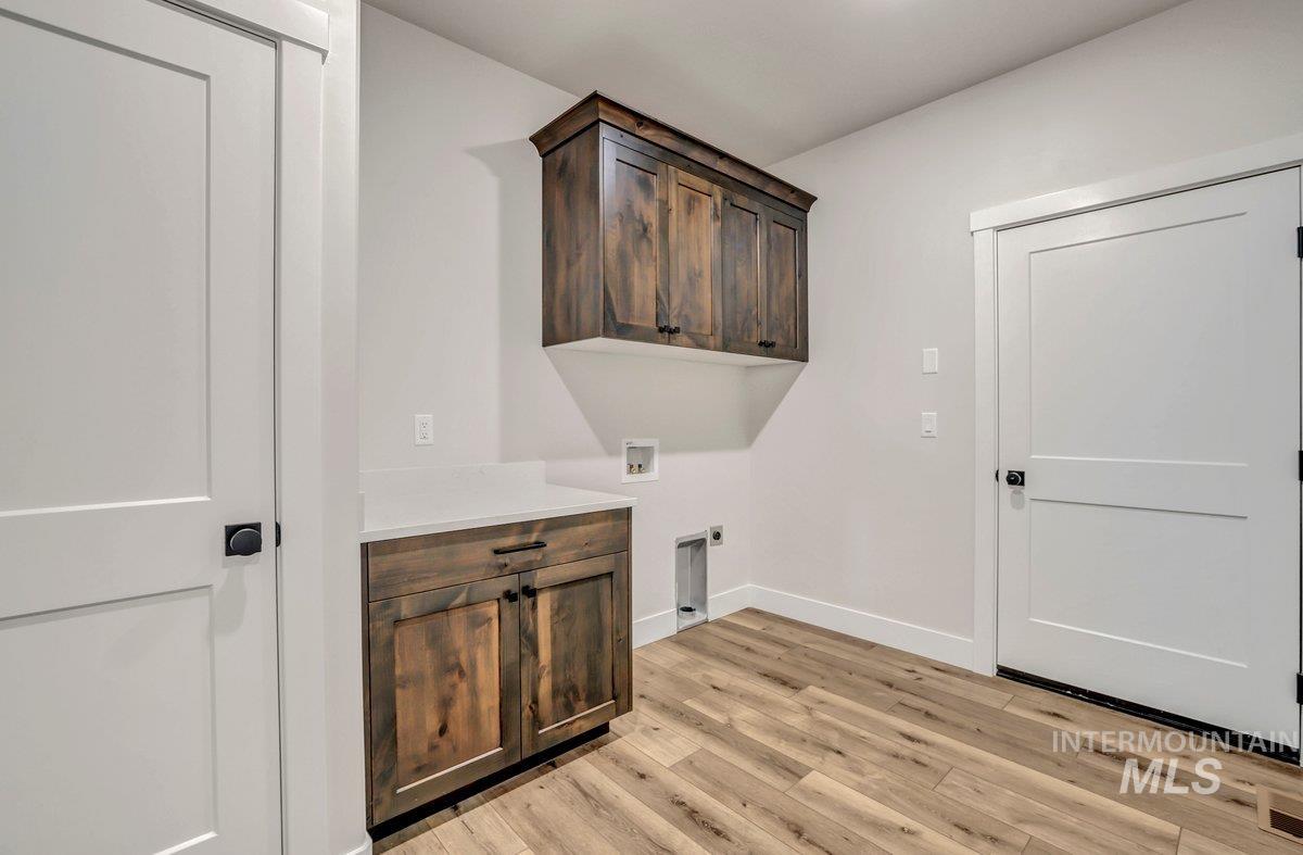 Washroom featuring washer hookup, light wood-style flooring, hookup for an electric dryer, and cabinet space