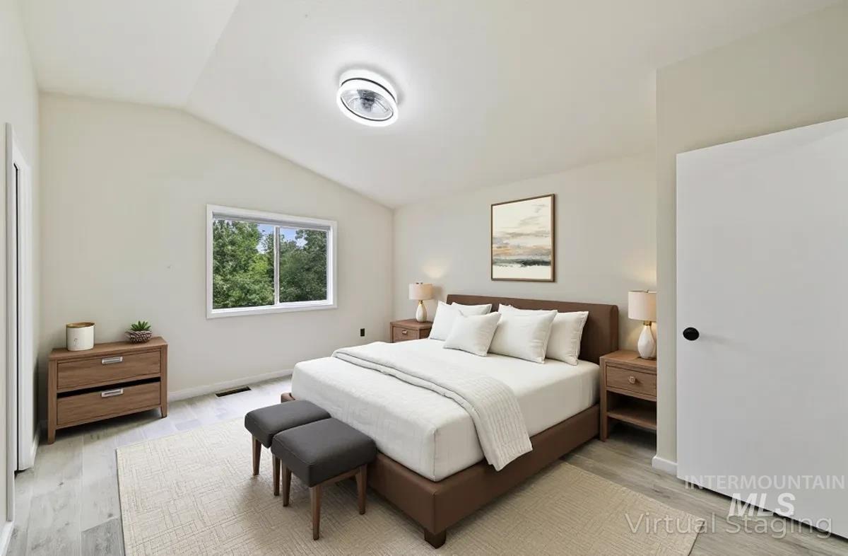 Bedroom with vaulted ceiling and light wood finished floors