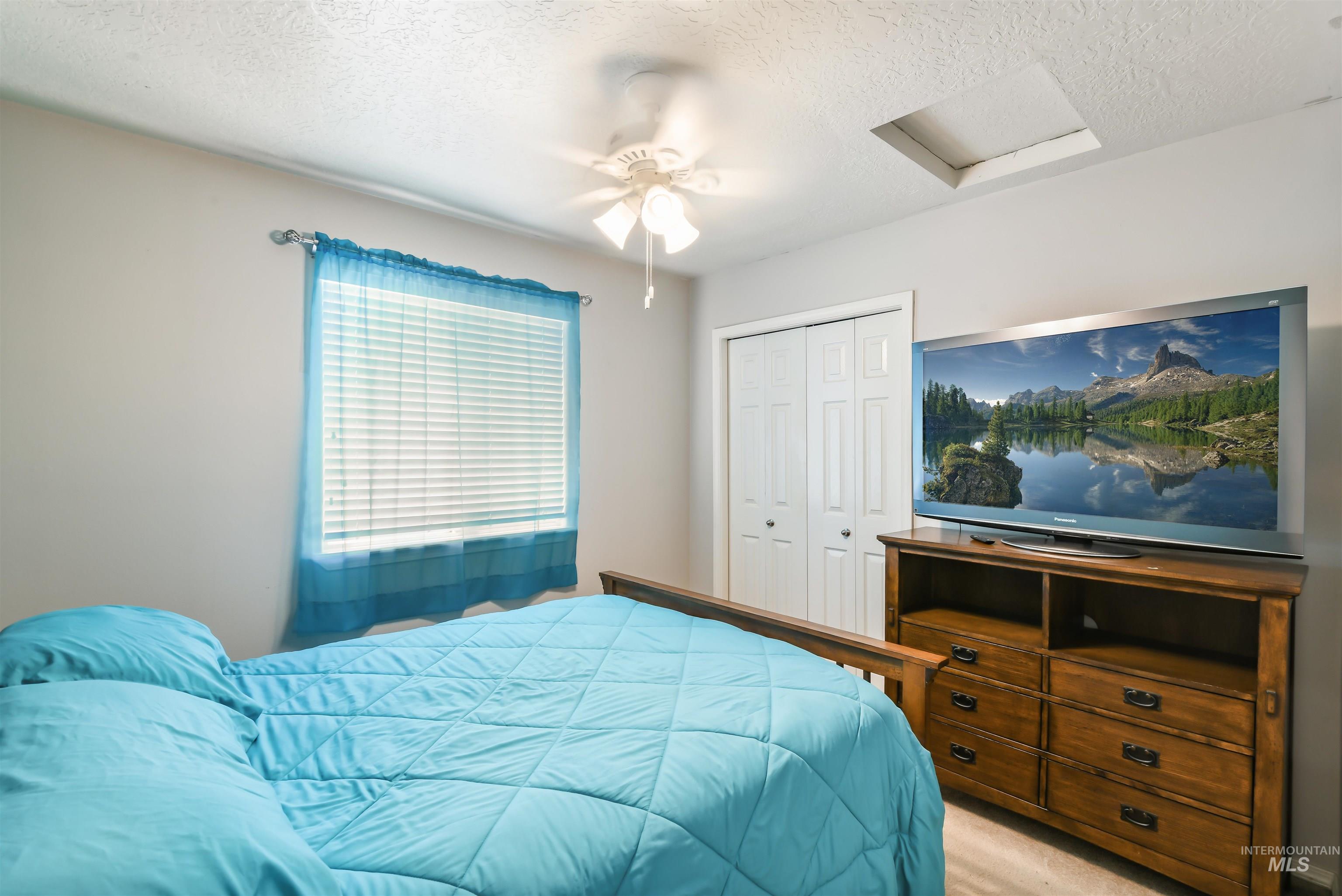 Bedroom with attic access, a textured ceiling, a closet, light carpet, and ceiling fan