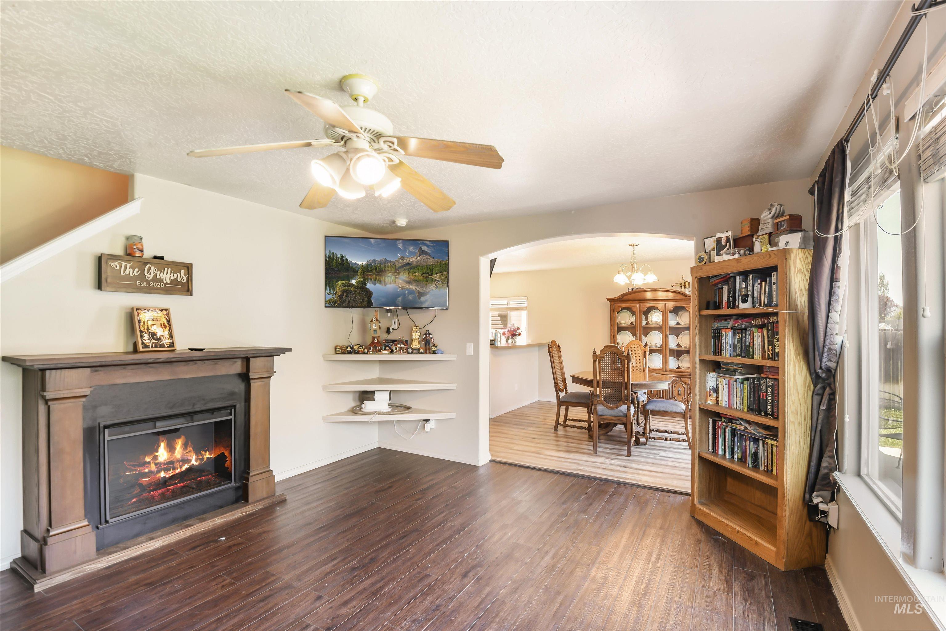 Living area featuring healthy amount of natural light, arched walkways, a glass covered fireplace, and dark wood finished floors