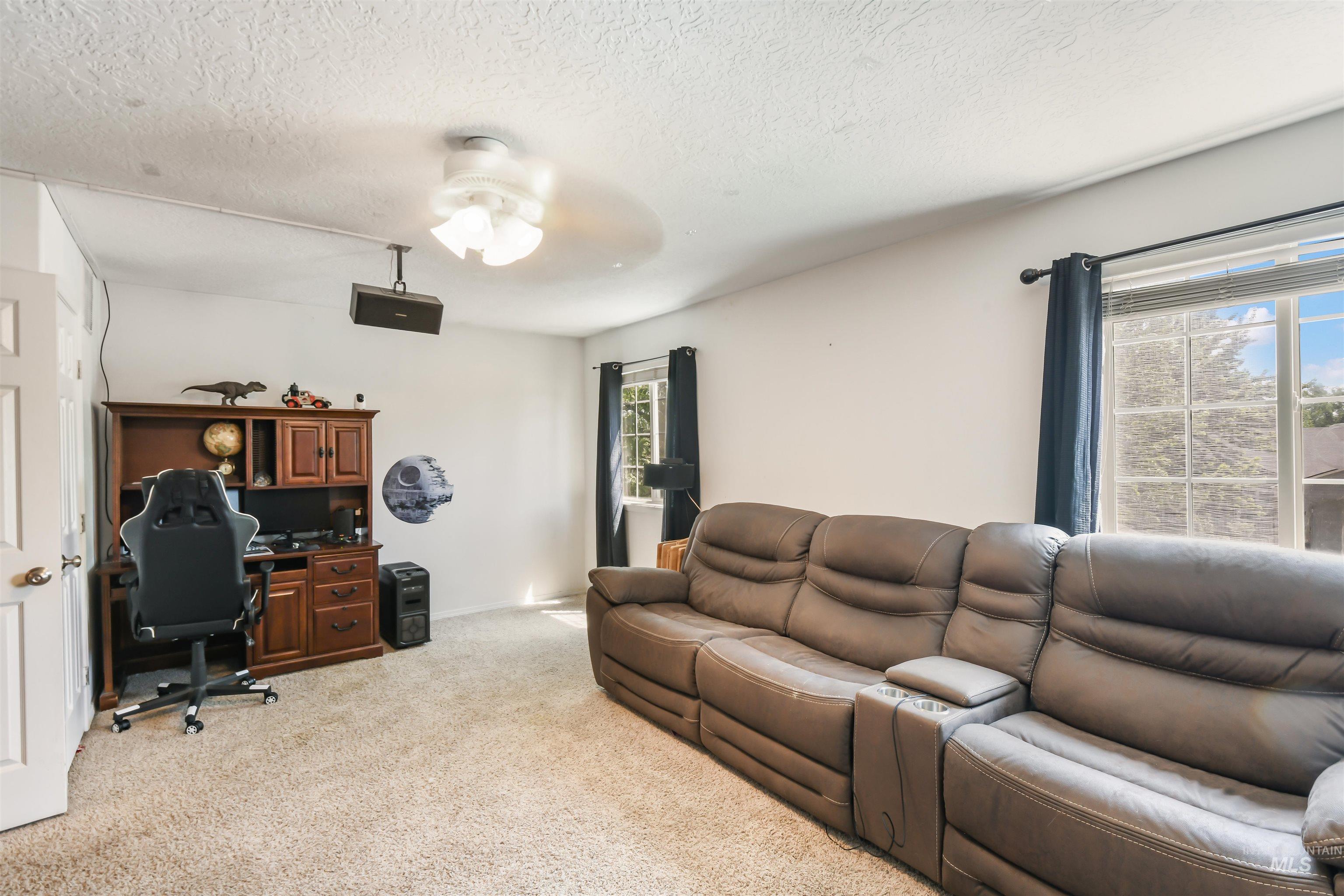 Living area with an office area, light colored carpet, a textured ceiling, plenty of natural light, and a ceiling fan